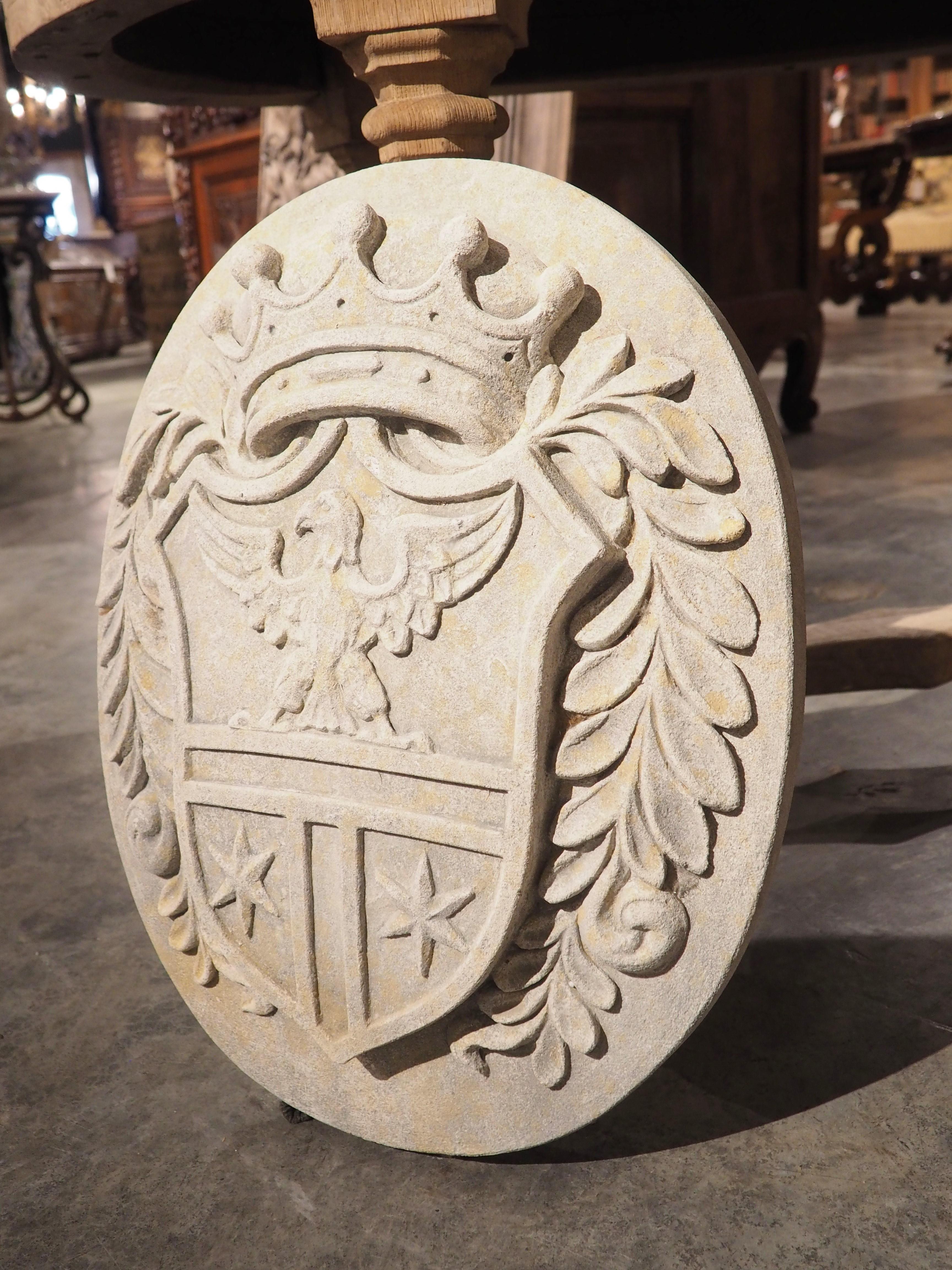 Hand-carved from Italian limestone, this coat of arms plaque with crown and eagle features both bas- and mid-relief motifs. Bas-relief is a sculpture technique where raised carvings have a shallow profile, while mid-relief ones have slightly more