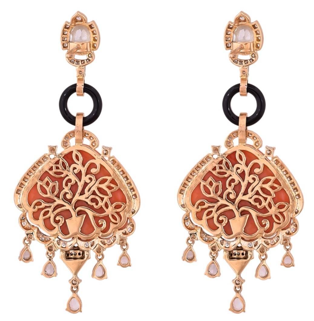 A beautiful pair of hand-made, art-deco looking earrings, using high-quality carved Italian Coral, Onyx and Diamonds. The intricate design details make this item very unique. The diamond studs on the top are 1 carat each. 

Material