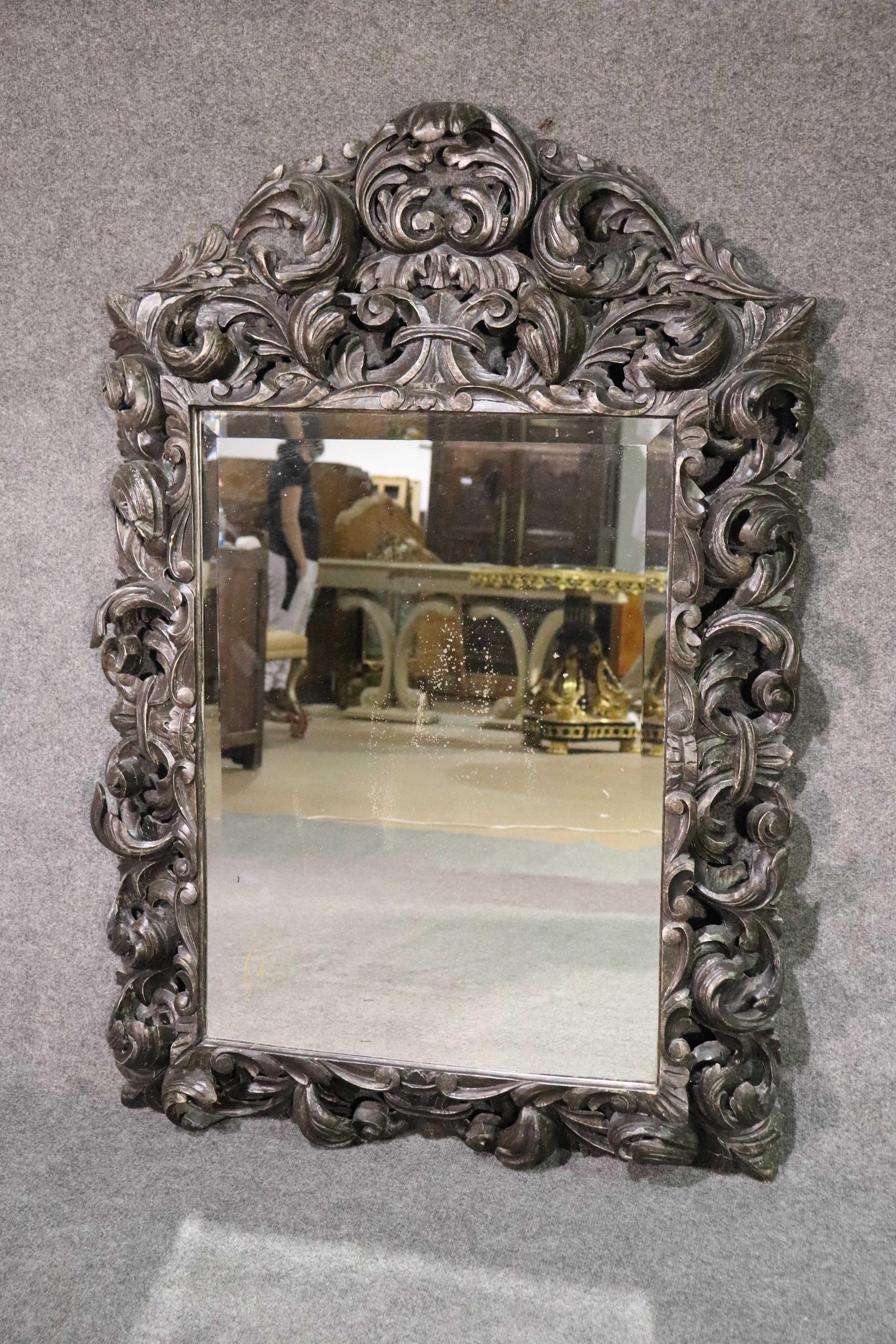 This is a gorgeous carved mirror designed in the Rococo style. The mirror was made in Italy of carved walnut and has a beautiful beveled glass mirror inset. The mirror measures 57 tall x 39 wide. It dates to the 1950s era.