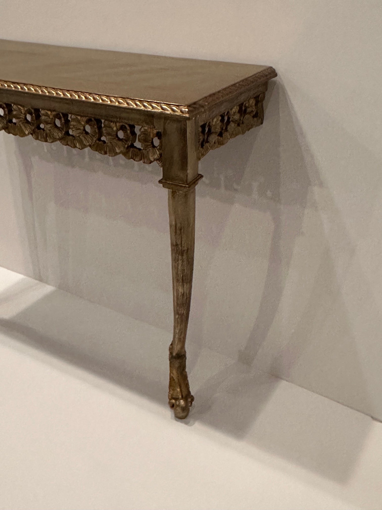 Lovely silver and gold leaf wooden narrow wall mounted console table from Italy having two elegant legs terminating in beautifully designed feet.