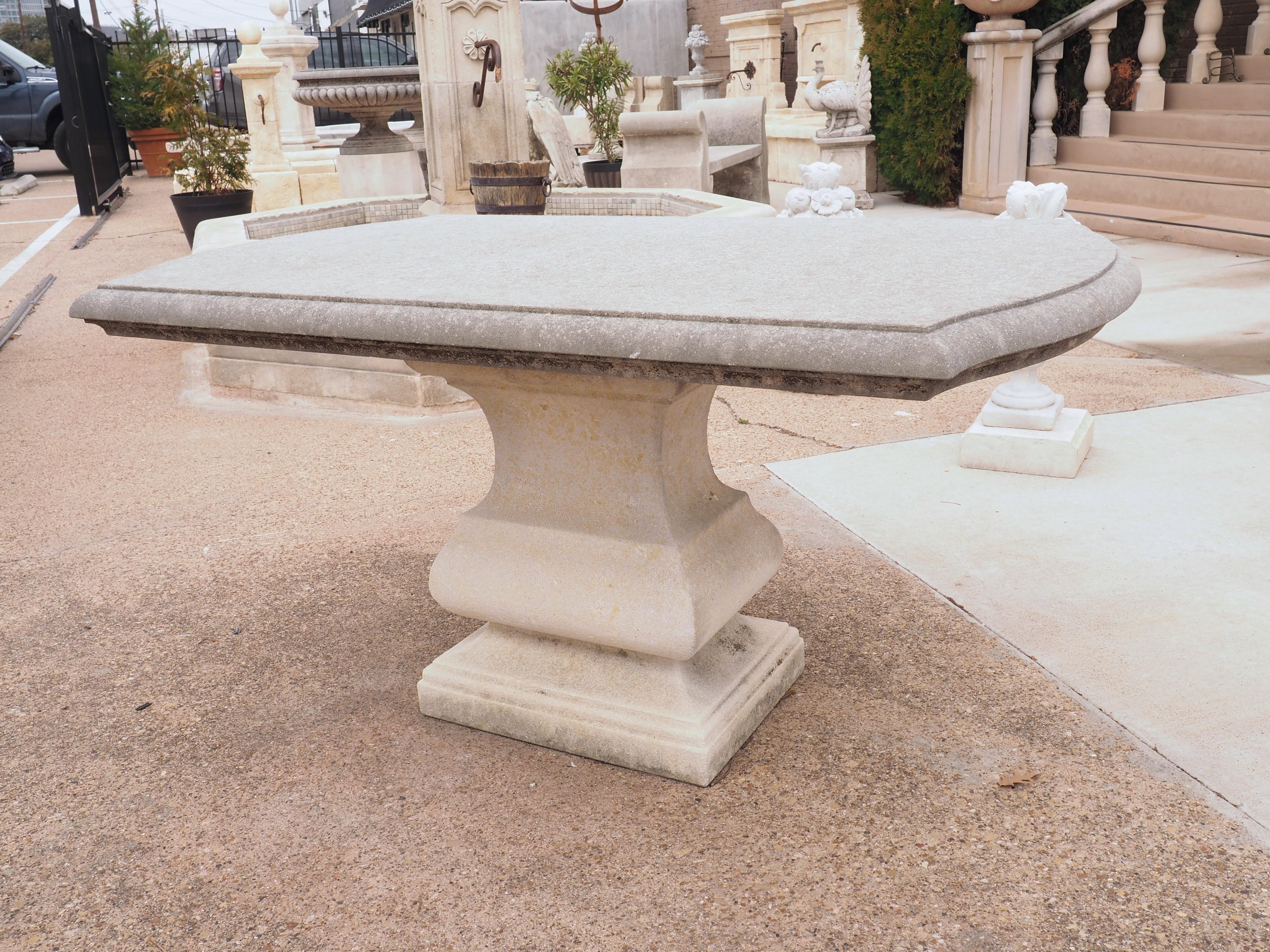 This table is made of carved Italian stone (not cast). It has been outdoors for the past few years, earning an authentic and aged patina, as evidenced by the darker surfaces and more pale support sections. The top is a gently curved rectangle paired