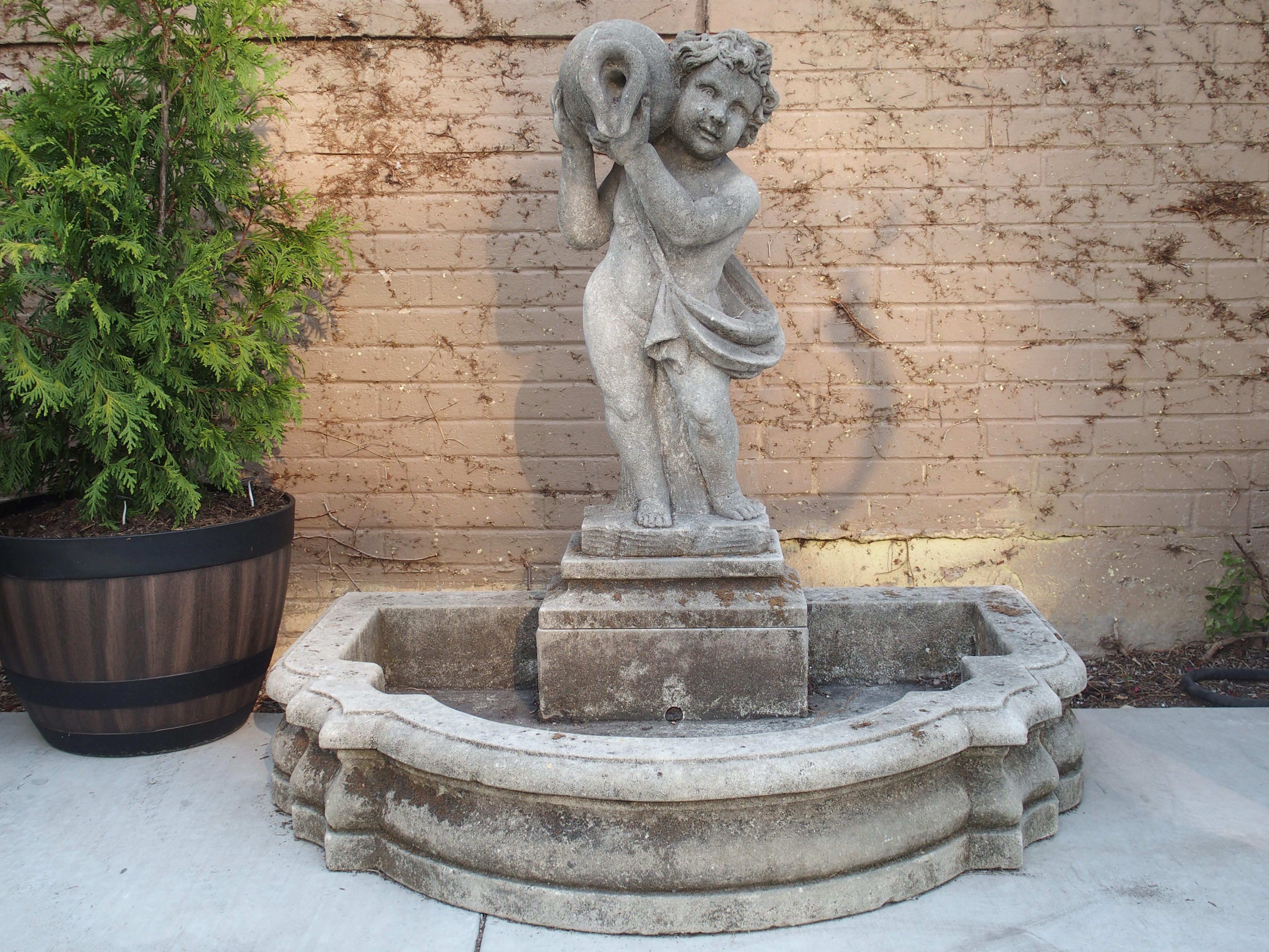 This hand-carved Italian fountain features a putto with a vase on his right shoulder, standing on a shaped plinth. The mouth of the vase is hollowed out, allowing for water to flow into the shallow self-enclosed basin below.

The putto is wearing