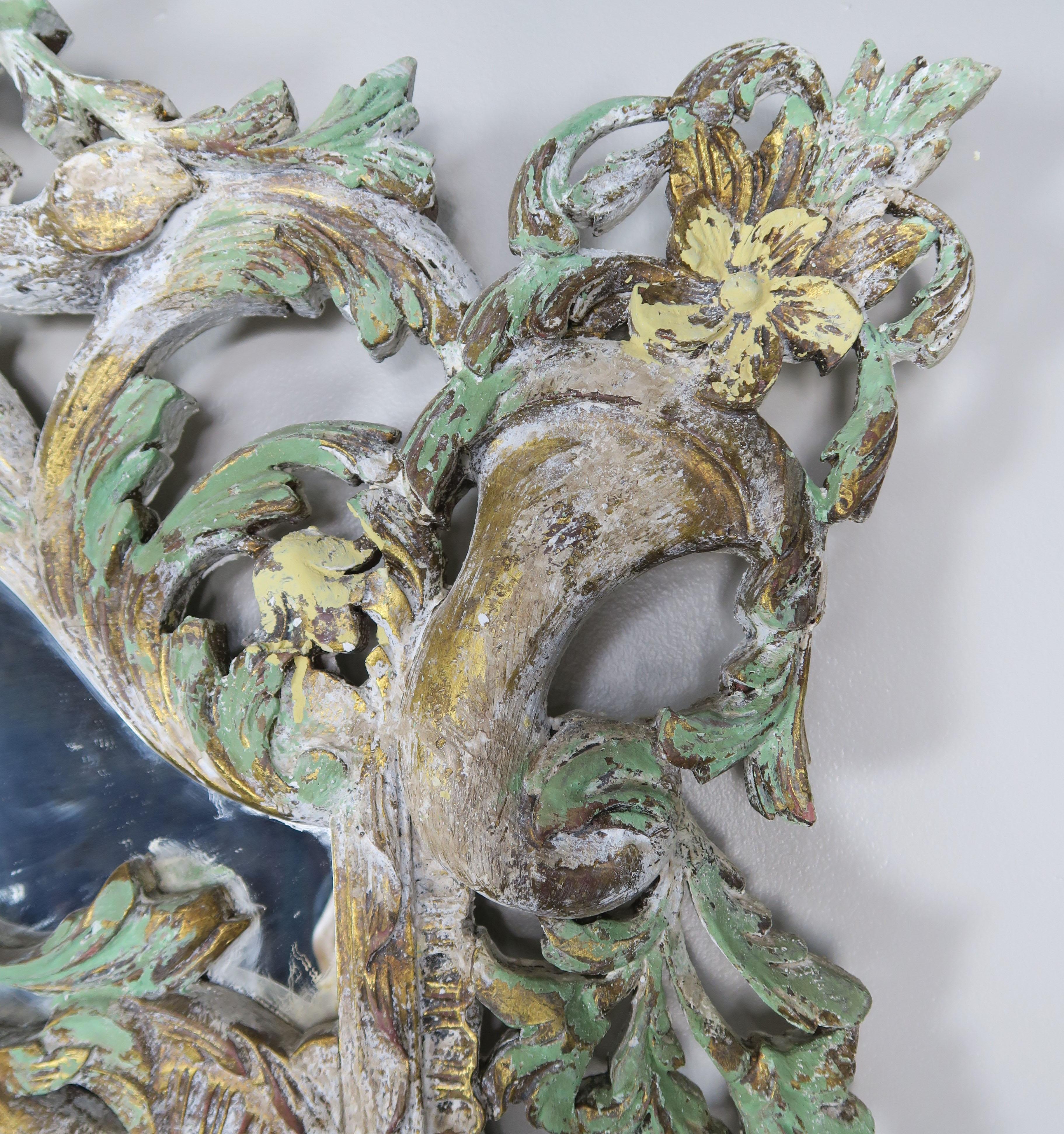 Monumental Italian Rococo style painted mirror with basket of flowers at top and cornucopias in both top corners. Carved garlands of flowers and swirling acanthus leaves throughout the detailed frame. Beautiful shades of antique white, green and