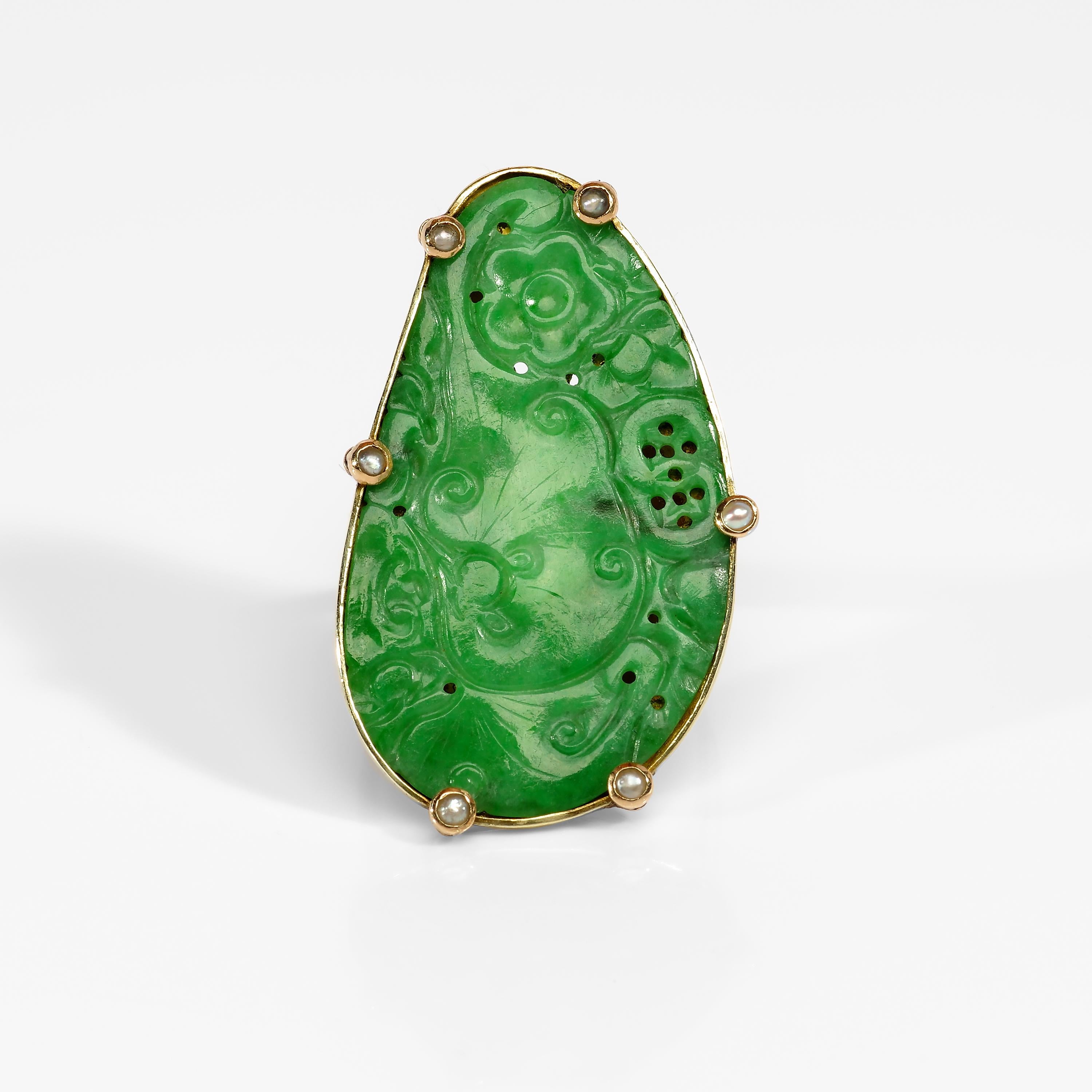 Depicting mushrooms, coins, and a hibiscus blossom, this spectacularly rich, evenly-toned natural jadeite jade has been meticulously carved, pierced, and thus imbued with meaning: longevity, prosperity, and splendor. The large jade carving measures