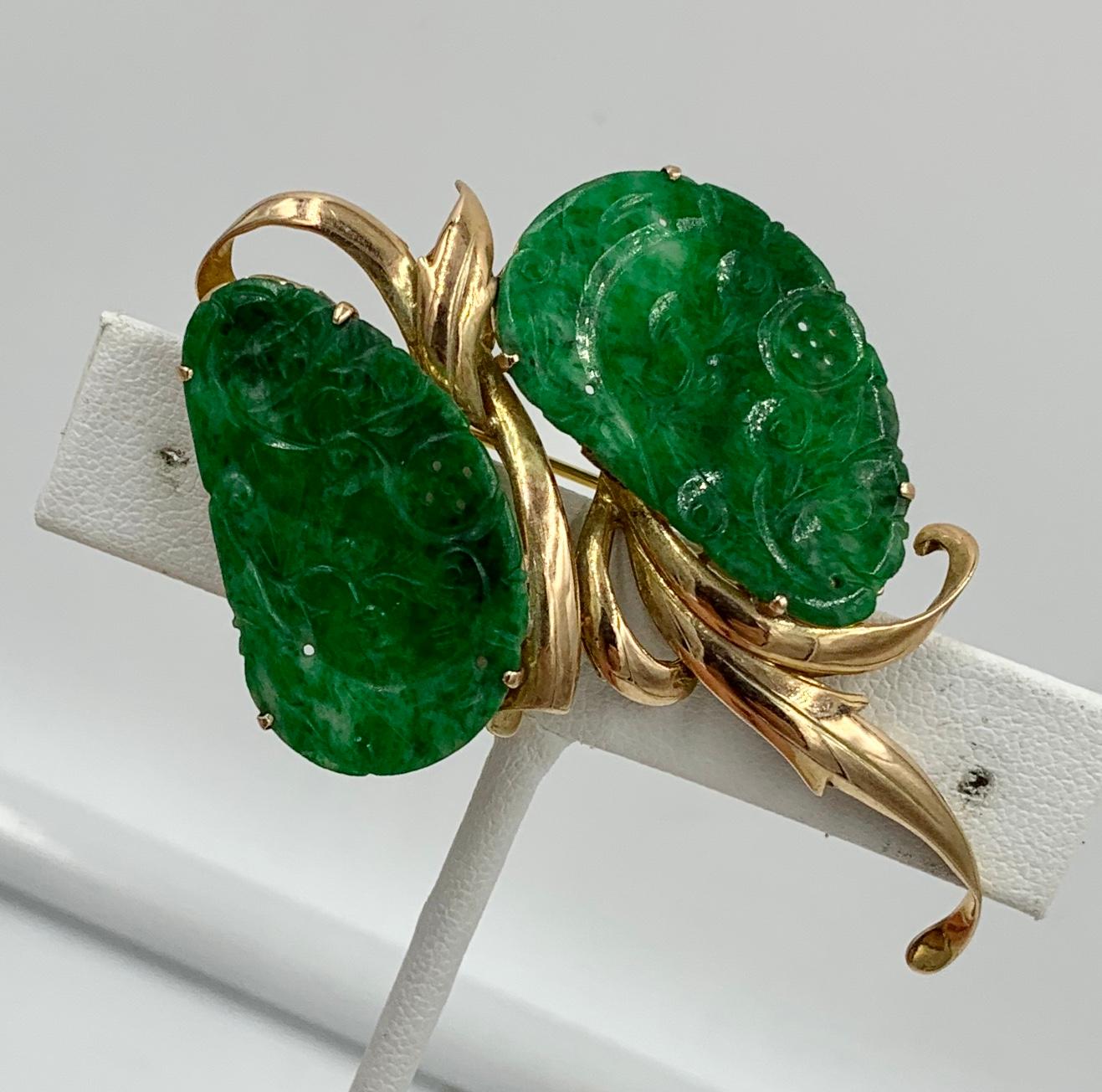 This is a stunning antique Carved Jade Brooch Pin in 14 Karat Yellow Gold marked H.K and dating to the Mid-Century Modern Period.  The two jade medallions have wonderful green color and are beautifully carved jade in a leaf form.  The jade is set in