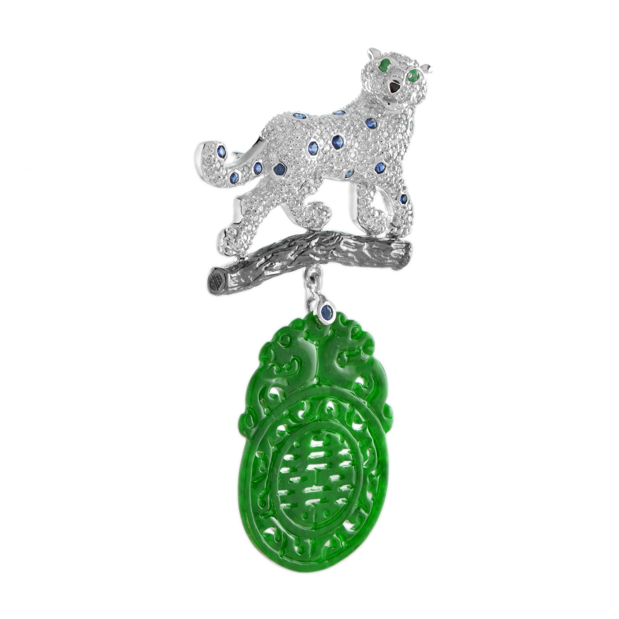 Spilla con pantera di diamanti che si arrampica su un ramo, realizzata in oro bianco 14 carati, con corpo incastonato di diamanti rotondi e zaffiro, testa parzialmente rotante, occhi incastonati di smeraldi e naso in onice. Qui sotto c'è una giada