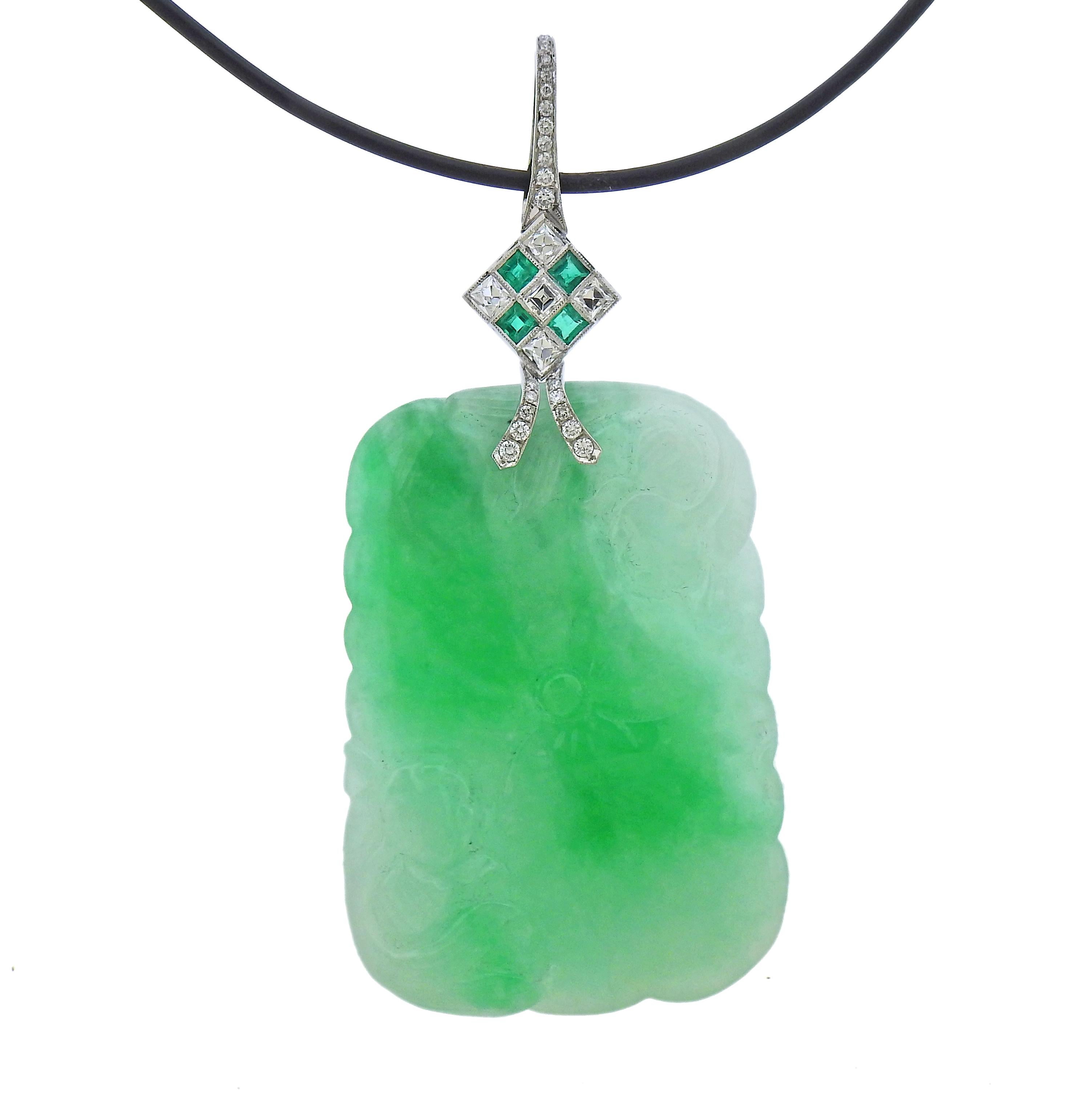 Large carved jade pendant, set in 18k white gold with approx. 1.20ctw in diamonds and emeralds, suspended on a rubber black cord necklace with 18k gold clasp. Pendant measures 97mm x 45mm (jade measures 64mm  x 45mm), Necklace is 17.5