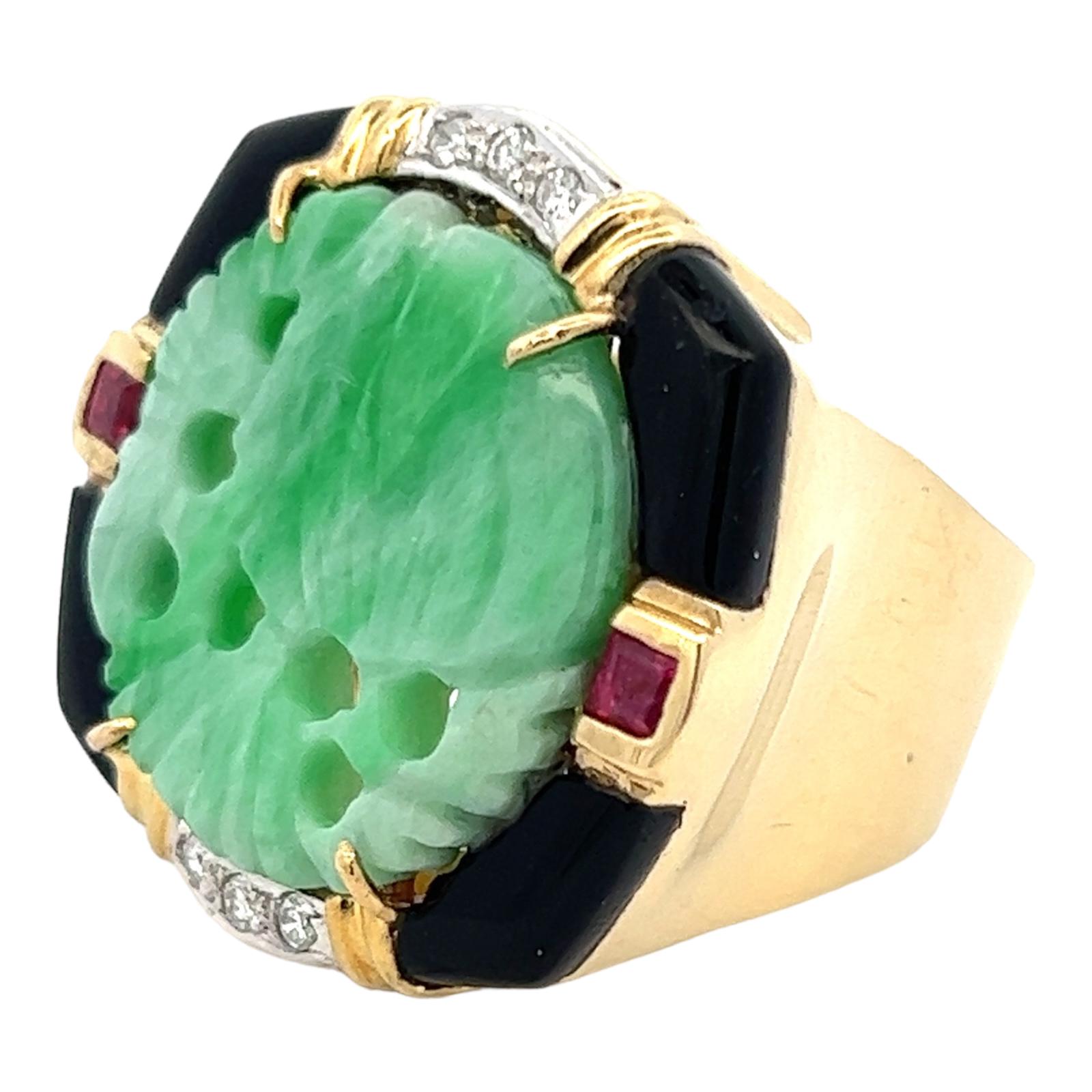 Beautiful carved jade diamond ring handcrafted in 18 karat yellow gold. The cocktail ring features carved green jade gemstone set in an onyx, diamond and ruby mounting. The 6 round brilliant cut diamonds weigh approximately .12 CTW. The top measures