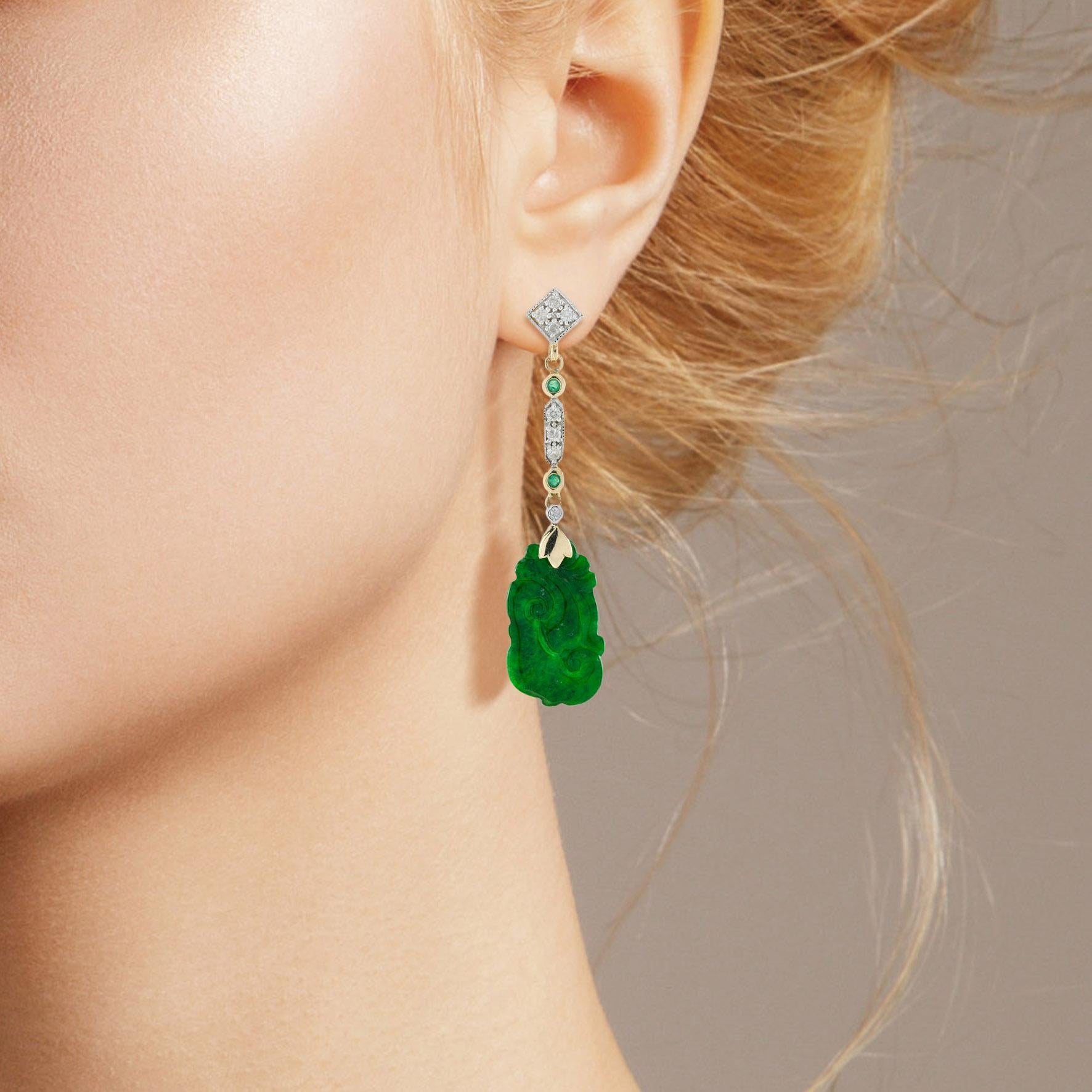 The natural jade in these lovely earrings has some very special shape. Both pieces have a strong green color and well carvings. The jade is suspended in a 9k yellow gold setting with emerald and diamond link on the top. The earrings transfer their