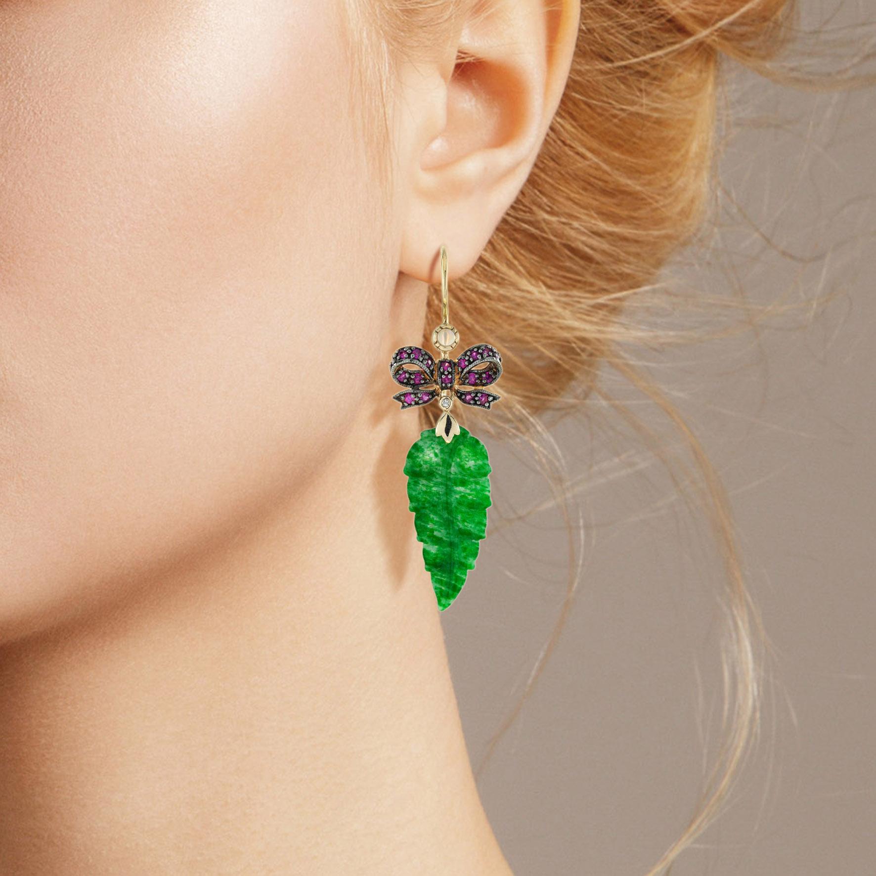 Die natürliche Jade in diesen schönen Ohrringen hat eine ganz besondere Form. Beide Stücke haben eine kräftige grüne Farbe und gute Blattschnitzereien. Die Jade hängt in einer Fassung aus 9-karätigem Gelbgold mit einer Rubinschleife auf der