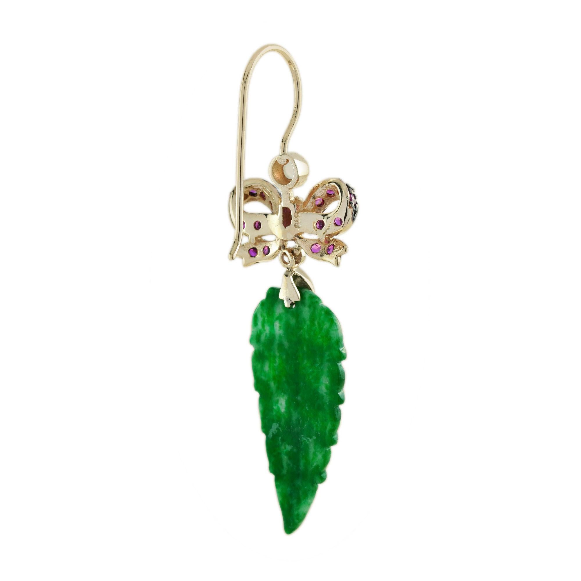 The natural jade in these lovely earrings has some very special shape. Both pieces have a strong green color and well leaf carvings. The jade is suspended in a 9k yellow gold setting with ruby ribbon bow on the top. The earrings transfer their good