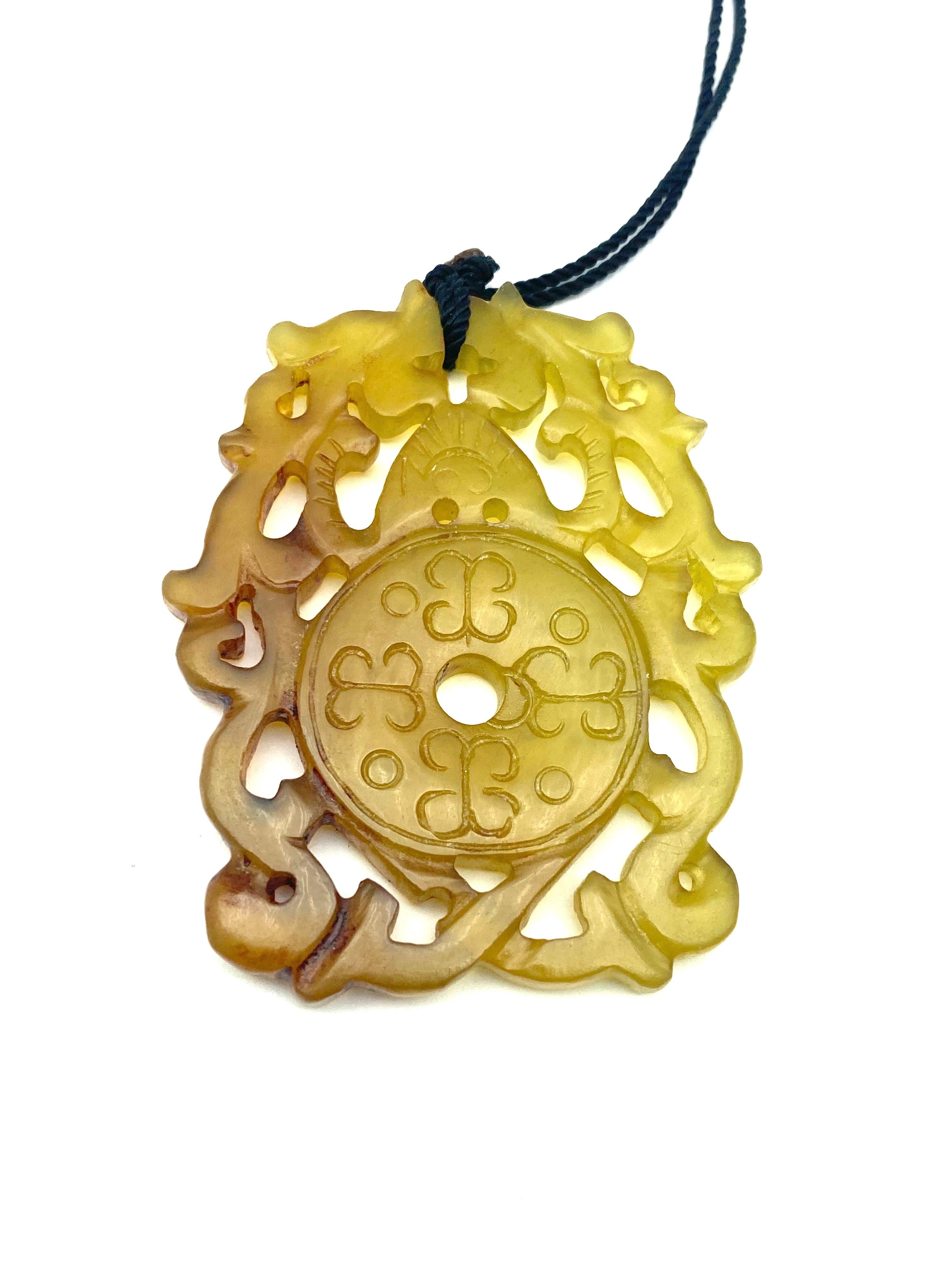 Carved Jade Anhänger schön detailliert und Messung 2,50 x 2,00 Zoll in breit. Die Tiefe der Jade ist mit 5 mm dauerhaft. Die Färbung der Jade ändert sich von gelb zu braun. 
Eine schwarze Kordel ist in den Anhänger eingeschlauft, so dass er bei 22