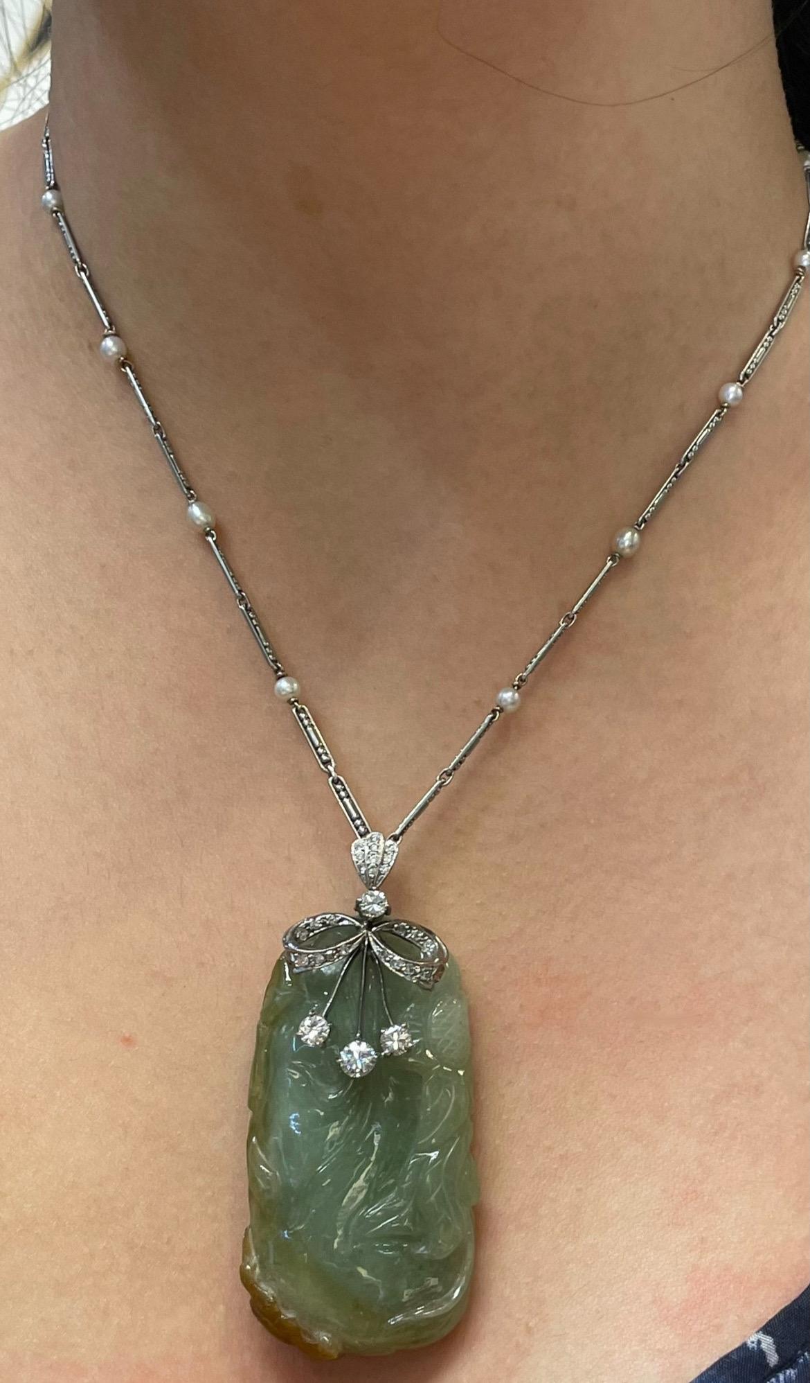 Carved Jade Pendant Necklace 

A carved jade pendant necklace around with round cut diamonds and 12 pearls on the chain. 

Approximate Diamond Weight: 1.05 carats
Approximate Chain Measurements: 17.5