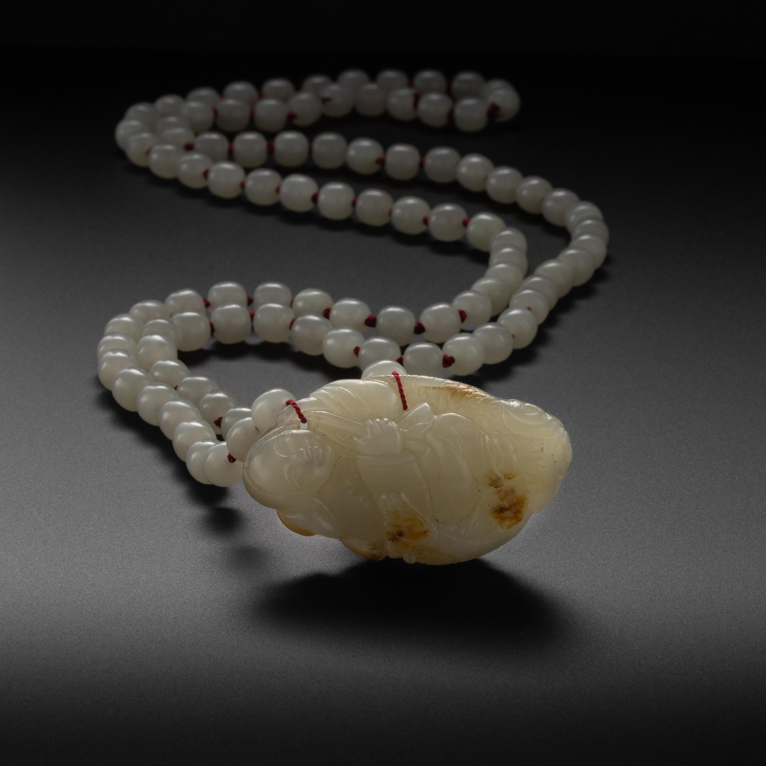 A superlative and genuine 19th-century white nephrite pebble hand-carved into a miraculously detailed Buddha figure has been paired with natural and untreated (contemporary) white nephrite jade beads that are an excellent color-match for the