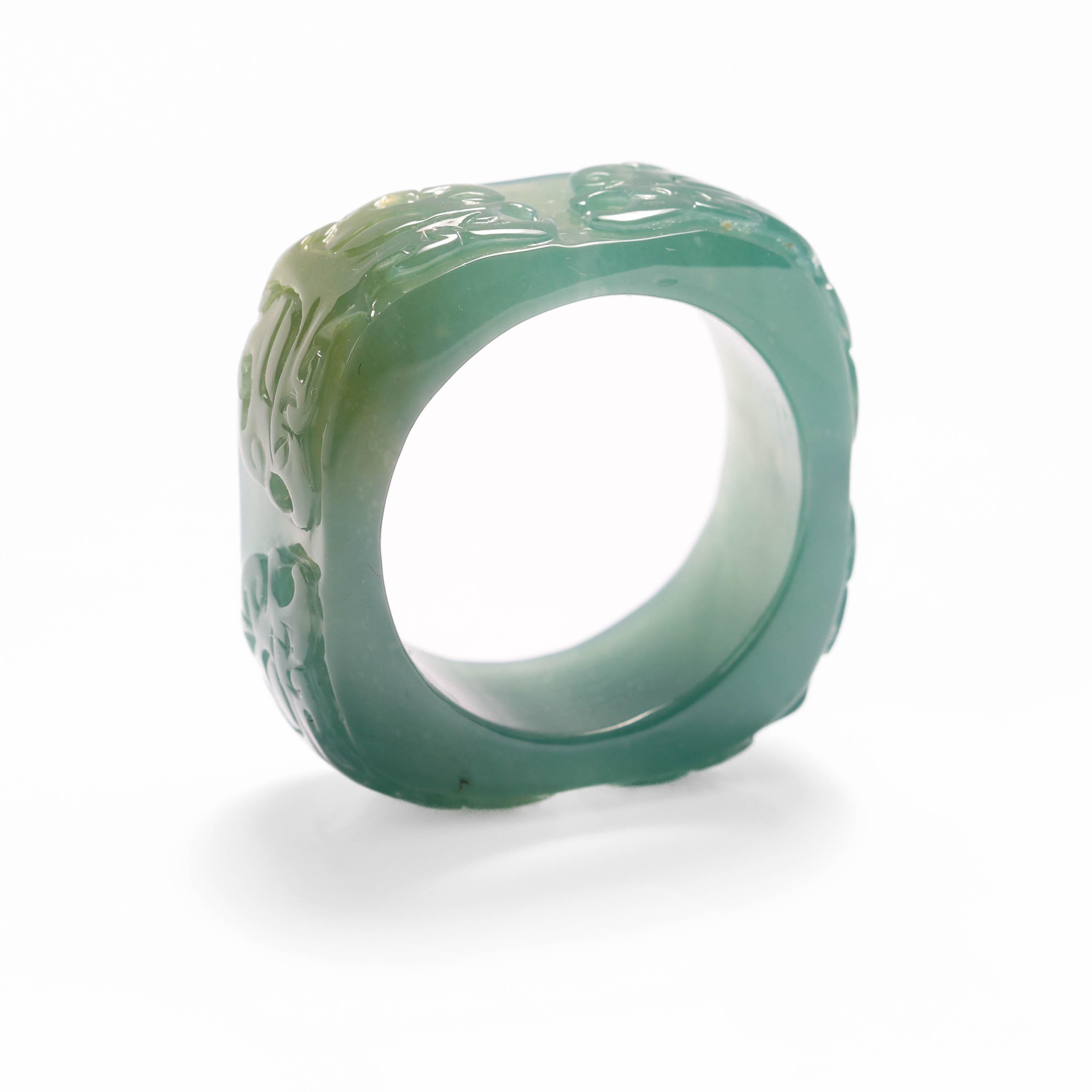 This large, unique ring was carved by hand from one piece of bluish-green natural and untreated jadeite jade. The ring has been carved in a square form with rounded corners and is surprisingly comfortable to wear. Intricate design elements have been