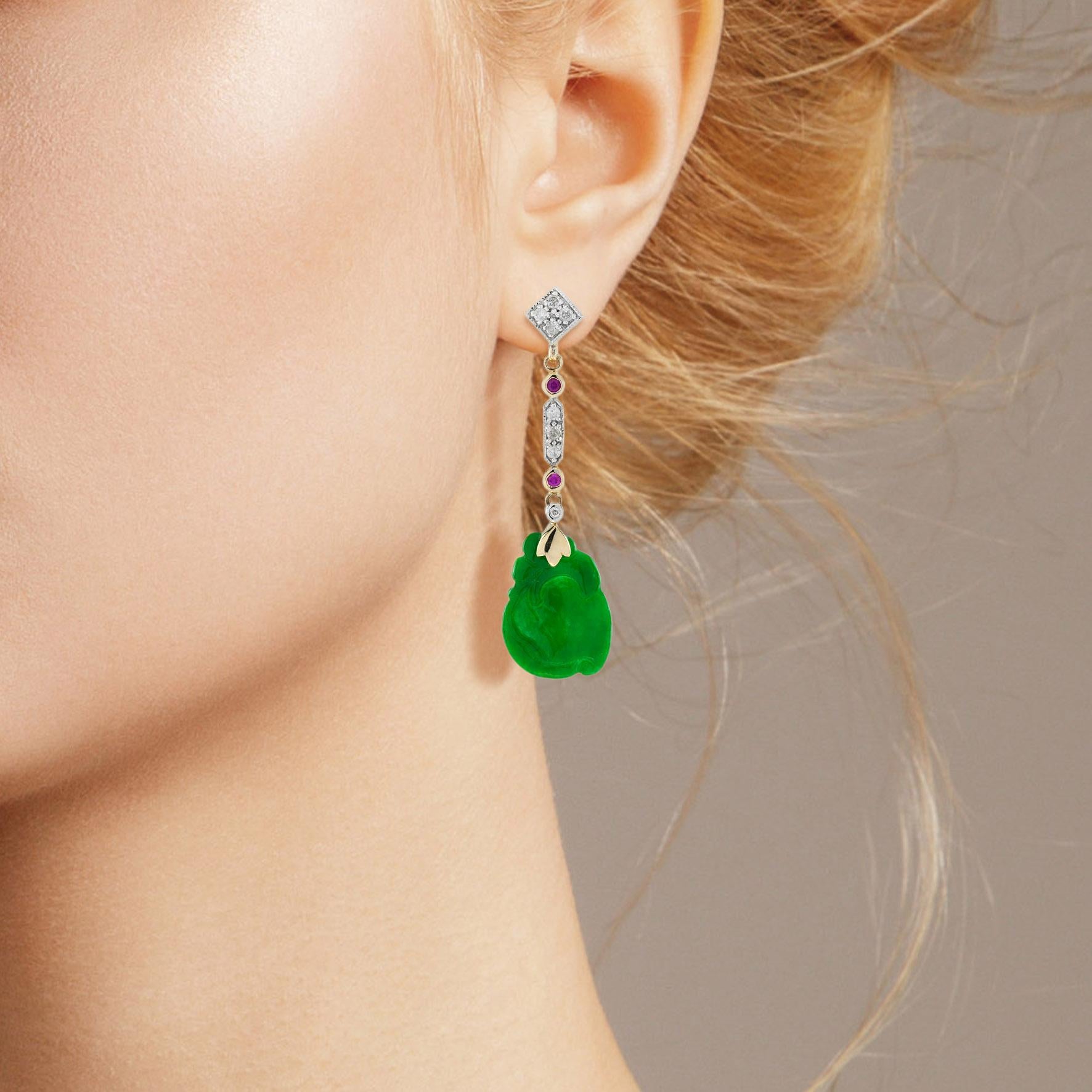 Die natürliche Jade in diesen schönen Ohrringen hat eine ganz besondere Form. Beide Stücke haben eine kräftige grüne Farbe und gute Schnitzereien. Die Jade hängt in einer Fassung aus 9-karätigem Gelbgold mit einem Rubin und einem Diamanten an der