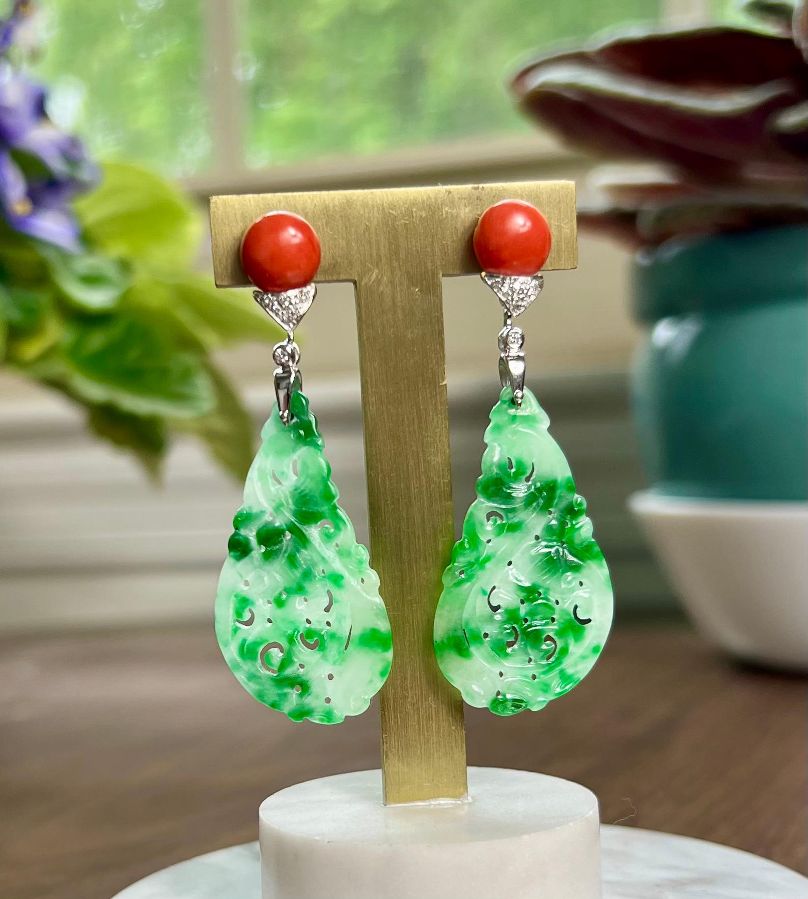 One pair of 18 karat white gold earrings each featuring one 9mm round cabochon coral stone, one carved color enhanced jadeite measuring 38.3mm x 20.6mm and four round brilliant cut diamonds, approximately 0.13-carat total weight with matching H
