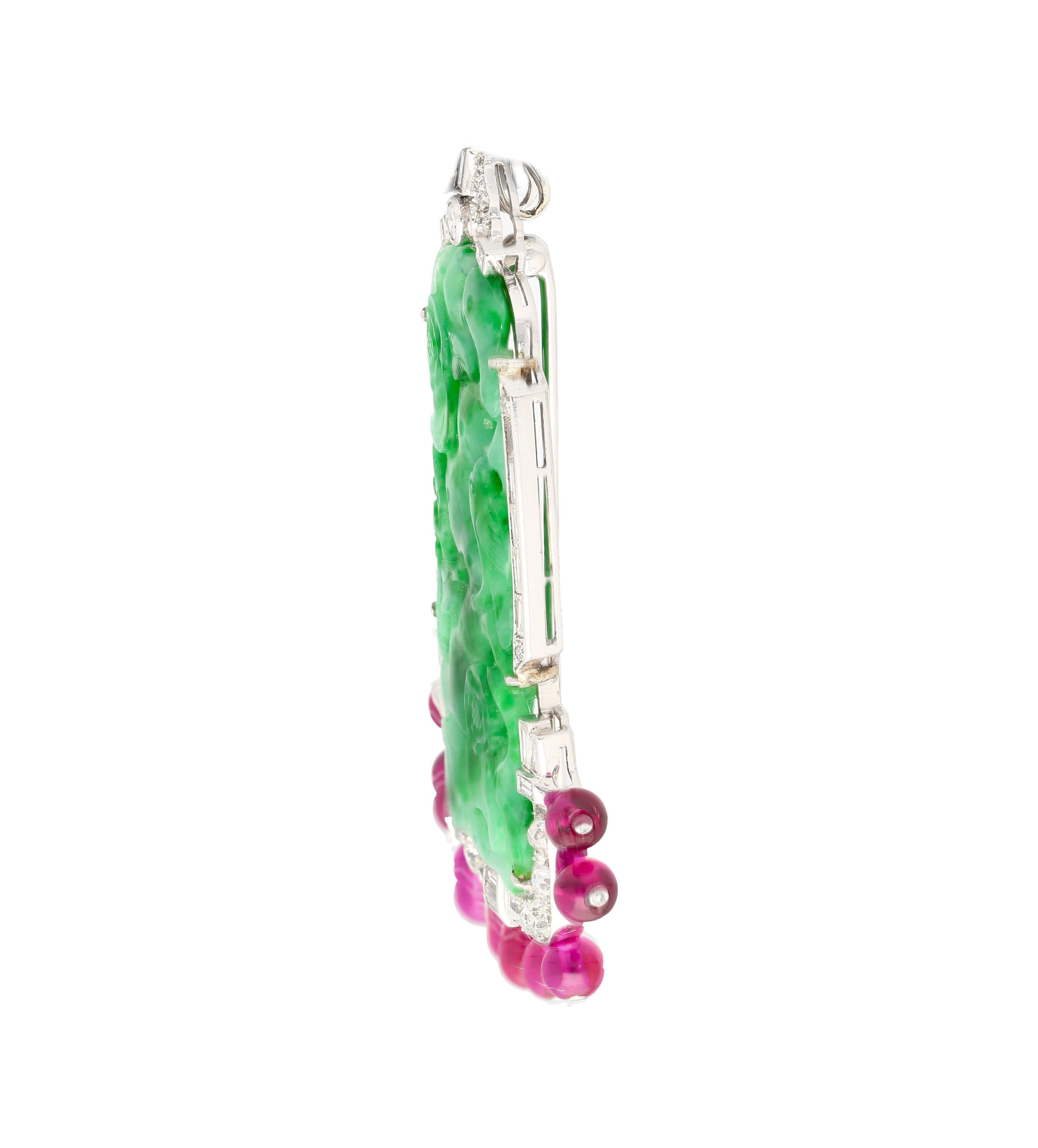 Jade and Diamond Pin with Ruby Beads in Platinum Pin. 

An artistic masterpiece, this pin features a prong set carved jadeite jade center stone. The jade is carved with holes and detailed texturing. It is paired with baguette, round, and fancy-cut