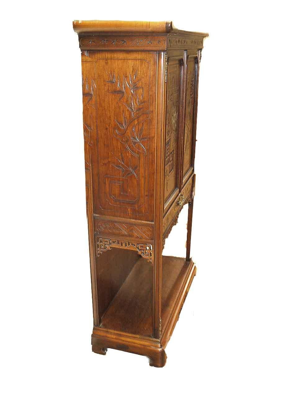 Carved Japanese inlaid cabinet, the cornice with ''turned up'' ends above foliate carved frieze, sides with carved leaves and arabesques, double doors with similar carving in addition to carved Japanese symbols and cartouches with mother of pearl