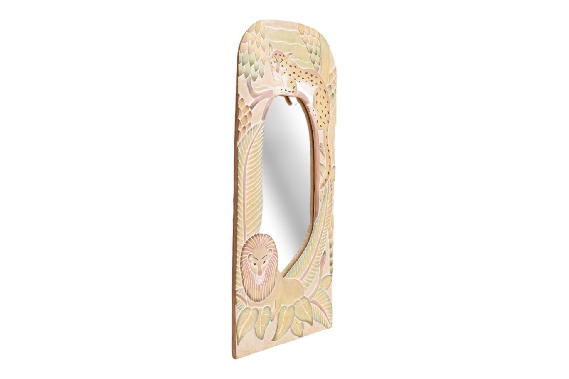 Miroir mural sculpté et peint à la main. Le cadre arqué est sculpté d'un guépard, d'un lion et de feuillages en relief. Peint à la main dans des tons pastel subtils de blush, de vert et de jaune, avec des détails noirs, sur une base beige. Câblé et