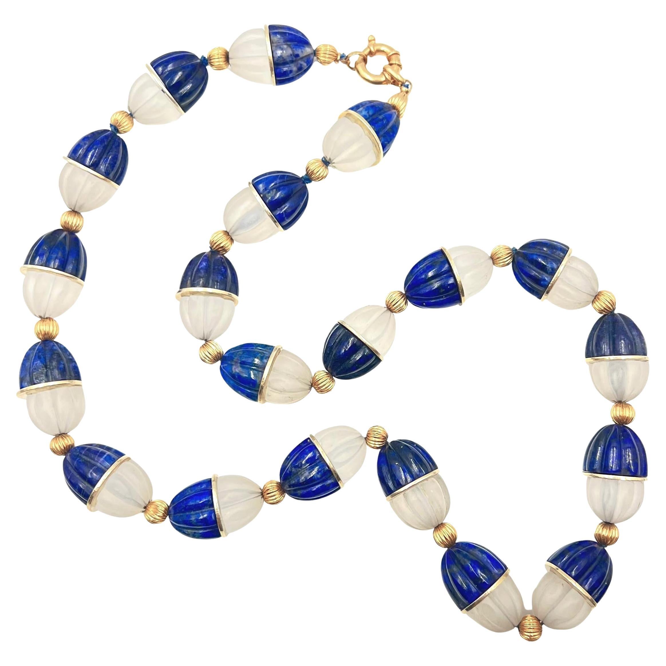 Bead necklace, composed of twenty half carved lapis lazuli and half carved frosted rock crystal beads, the halves joined by a central flat yellow gold disk. In between each of these larger beads are smaller 6mm 14k yellow gold fluted beads.  14k