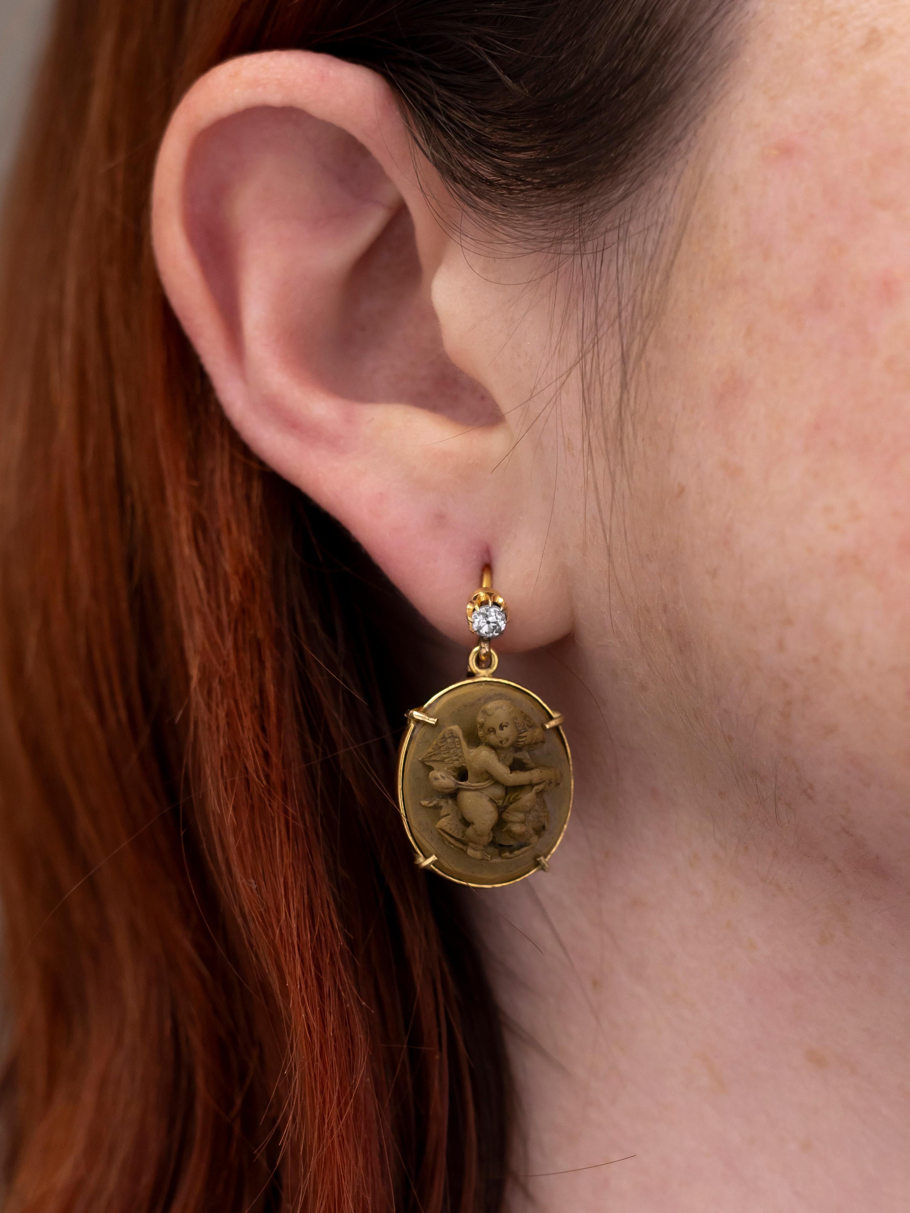This pair of earrings have been crafted from 19th century jewellery components and present in the Victorian taste. The earrings stem from an old cut diamond set stud from which a carved lava cameo drop hangs. The old mine cut diamonds in the studs