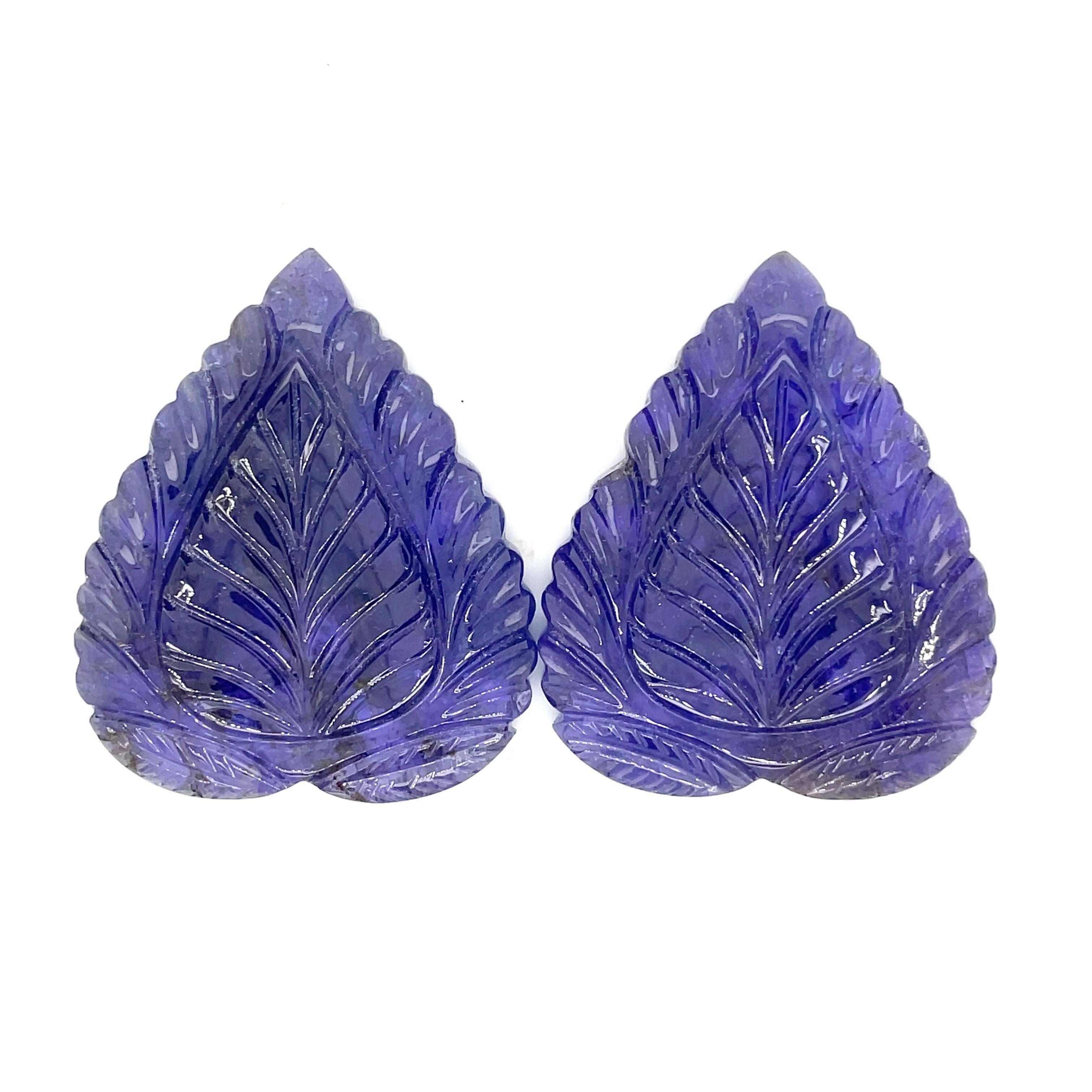 This exquisite duo of Tanzanite gemstones weighs a stunning 164.44 cts.

They are carved to resemble delicate leaves and are a true testament to nature's artistry and unparalleled beauty, making them a must-have addition to any jewelry