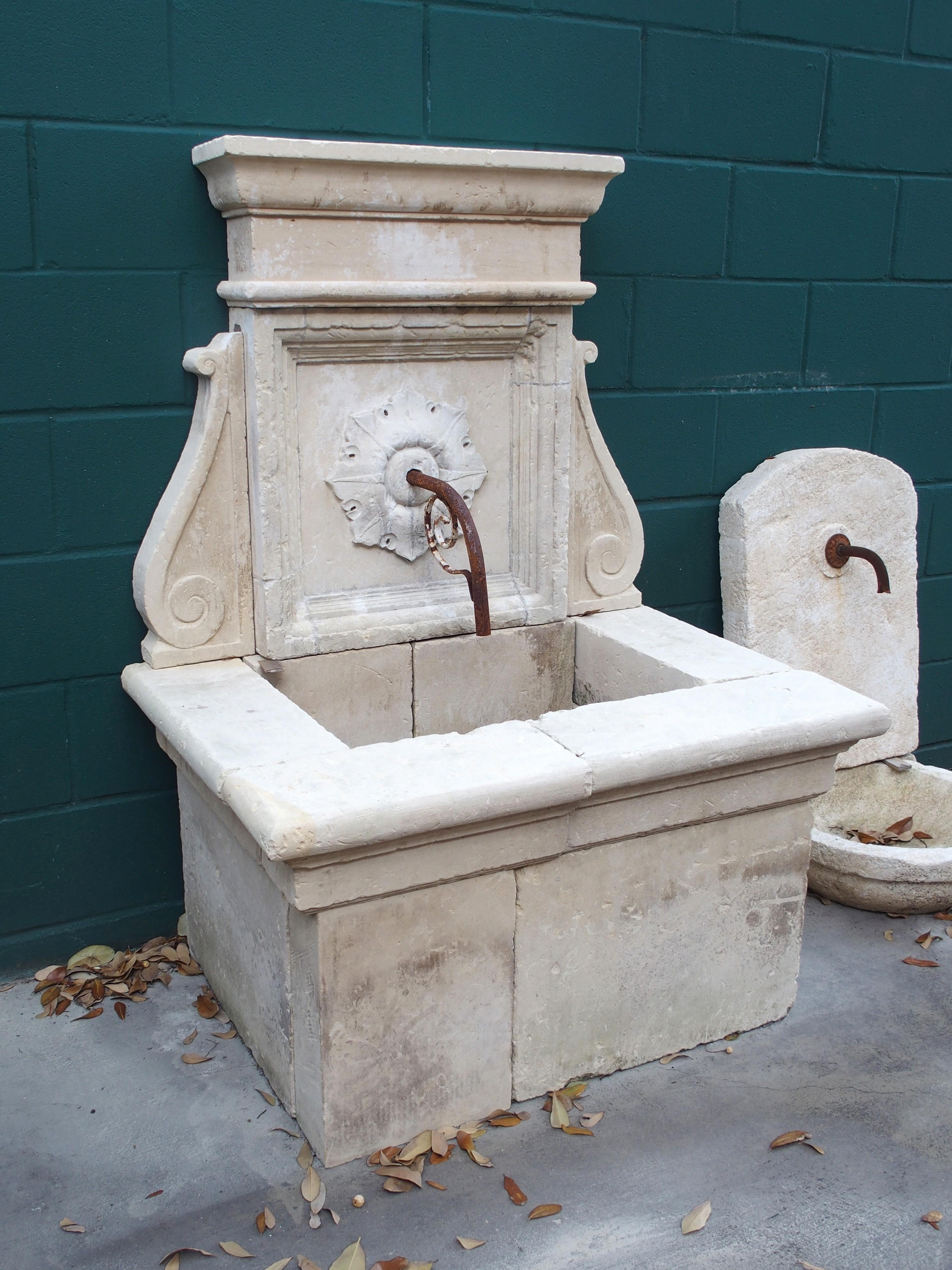 Consisting of 14 pieces of hand-carved limestone, this small wall fountain was produced in Lecce, in Southern Italy. The top entablature features a thick ogee molding beneath the cornice and a quarter-round protrusion near the base, above a square
