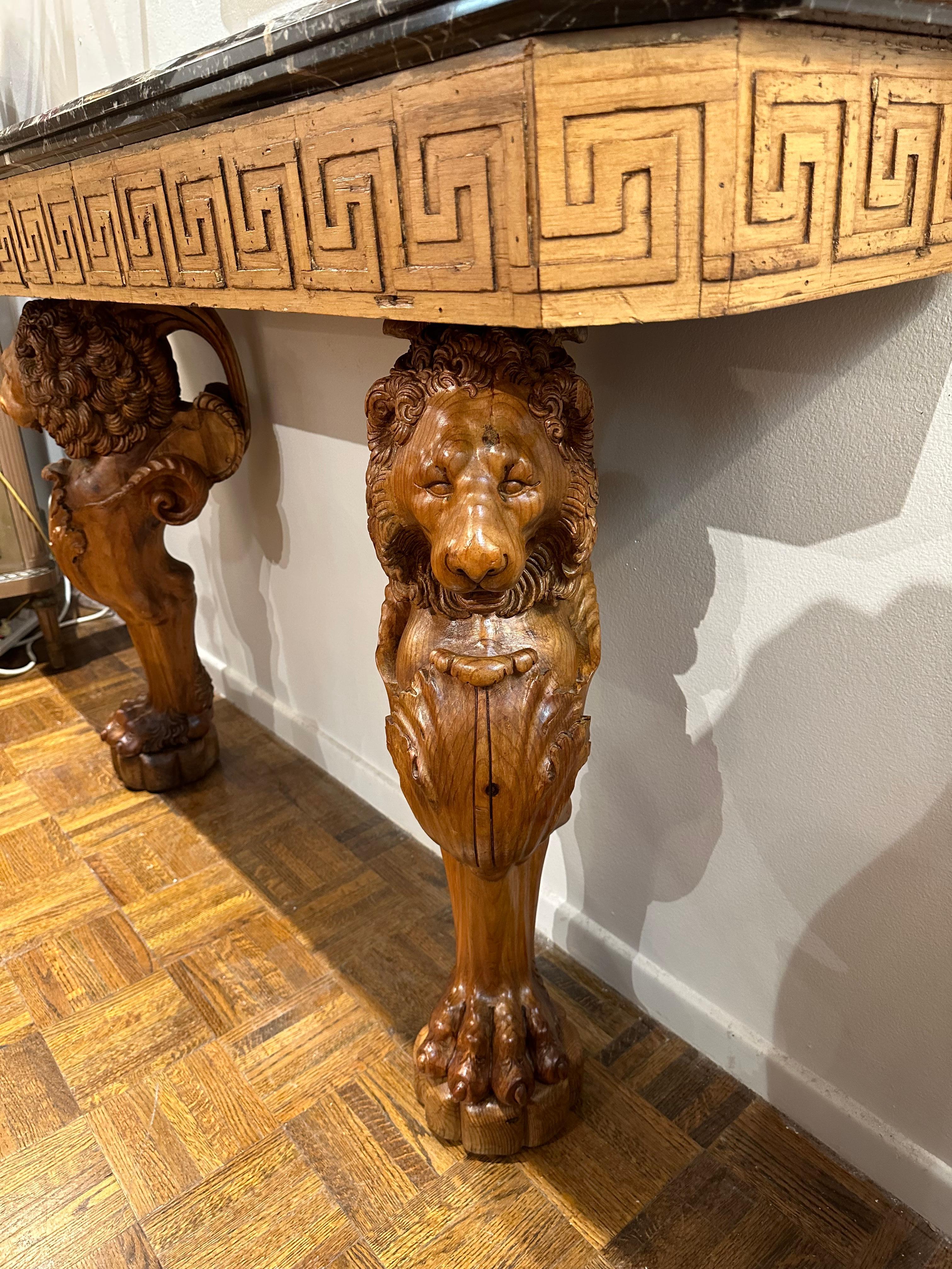 Beautifully detailed carved lions with Greek Key fret design panel, holding up beveled marble top.  Dramatic console table for your entry..