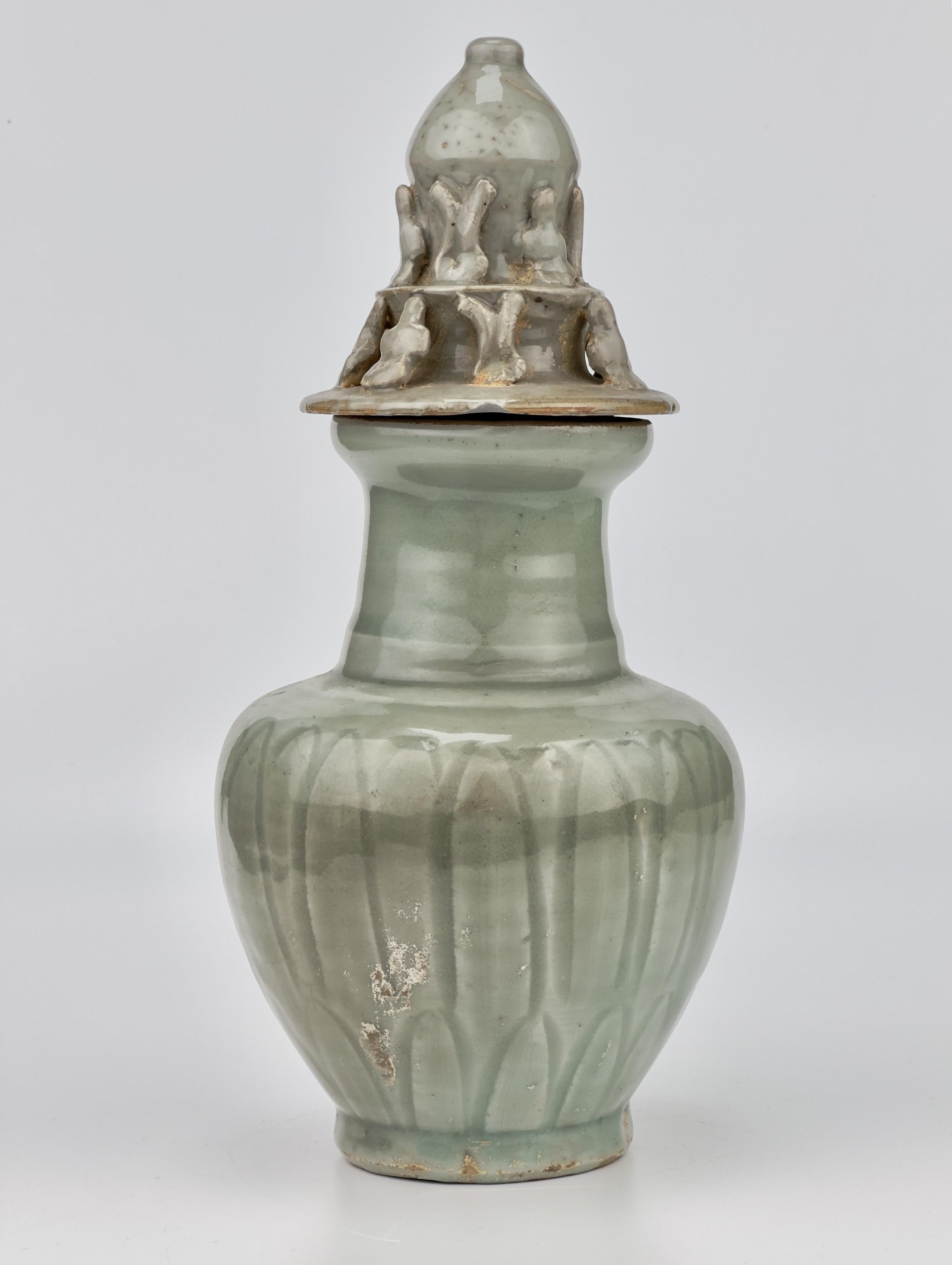The vase features a ribbed body, subtly enhancing its graceful contours, and is topped with a uniquely sculpted lid adorned with figurative elements.

Period : Song Dynasty
Type : Celadon
Medium : Longquan ware
Size : 26cm(Height) x 7.5cm(Mouth