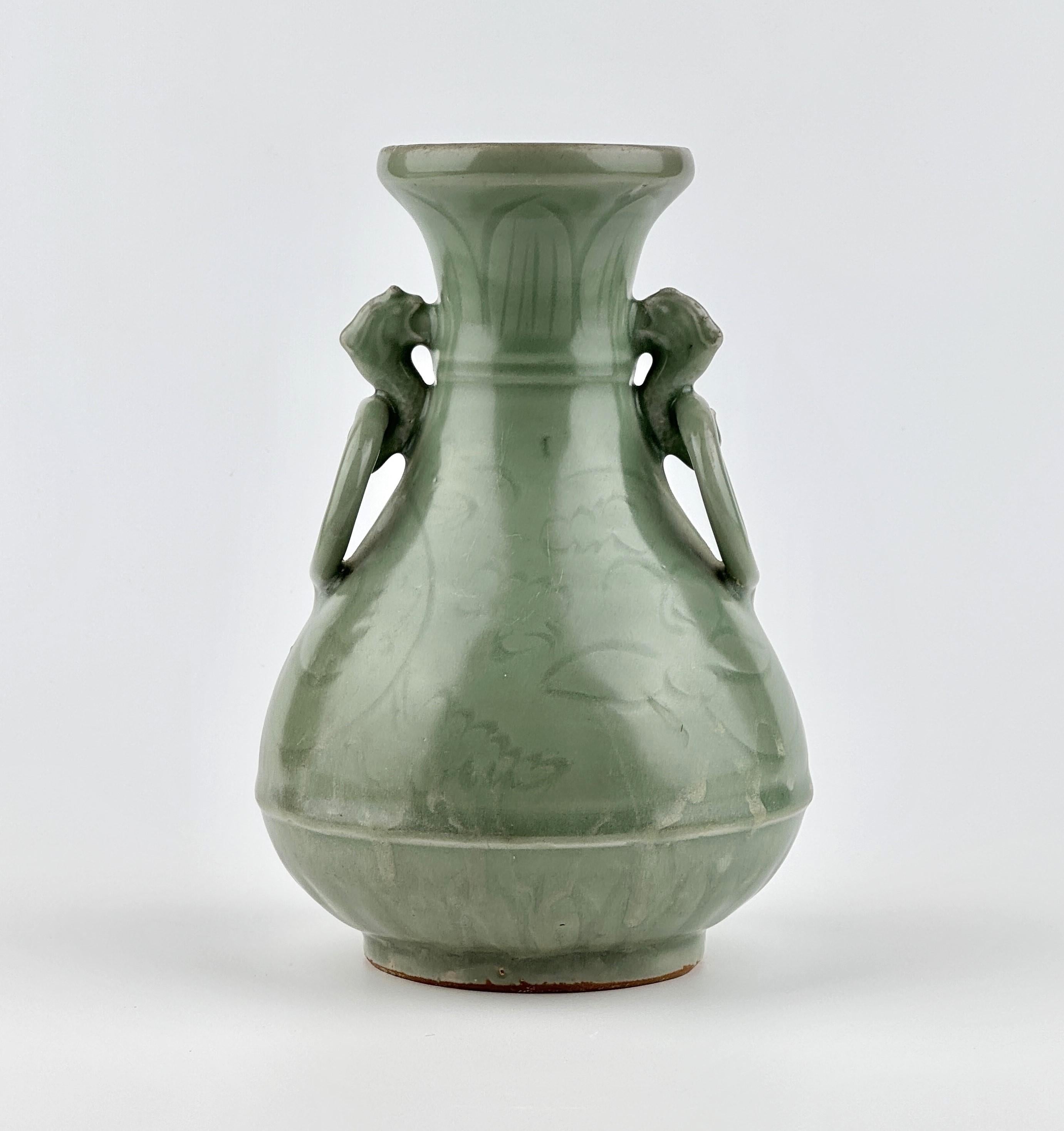 A graceful baluster form with a flared mouth, a rounded body, and a slightly raised foot. The vase features two intricate handles in the shape of animal figures holding large looped rings, adding a dynamic and decorative touch. The surface is