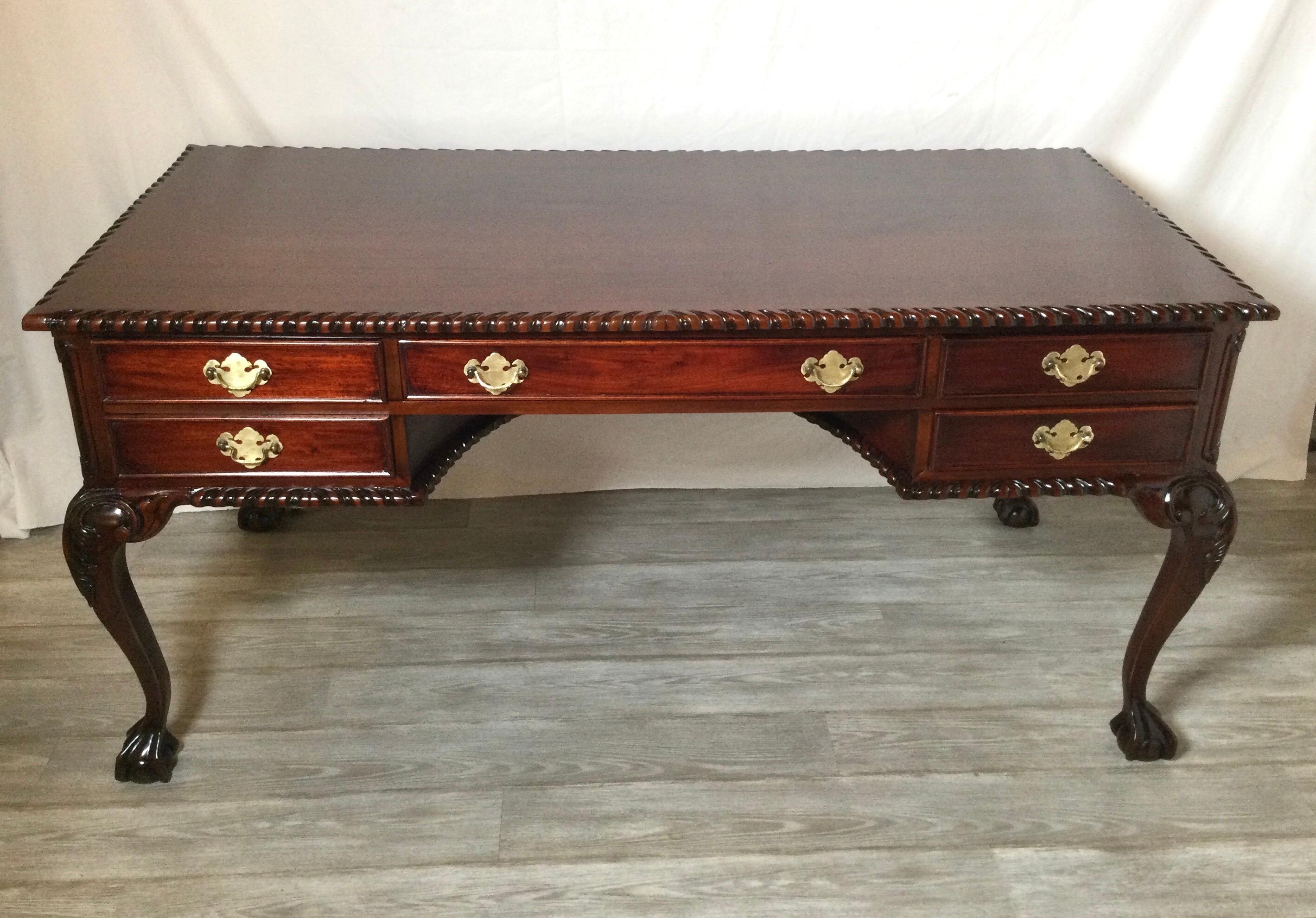 Nice sized hand carved mahogany writing desk with ball and claw feet and gadrooned edges. The rectangular surface with a center drawer flanked by two drawers on each side. The cabriole legs with carved details on the knees.
Dimensions; 64'W X 32