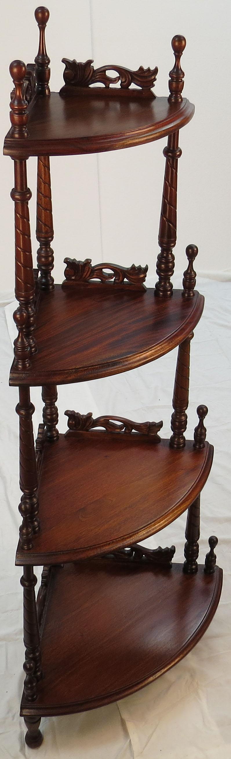 This stunning small four-tier corner whatnot was made in England sometime, circa 1960. It’s done in mahogany wood and features turned and tapered columns that are capped off with turned finials. The front edges of each shelf is curved out and
