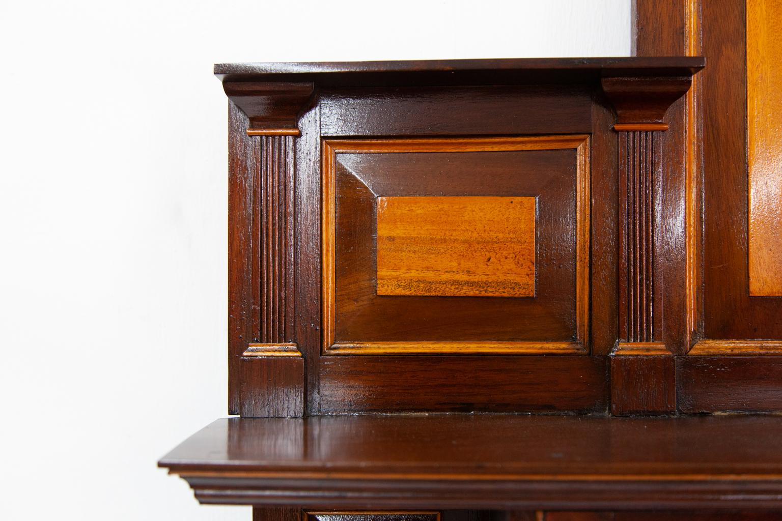Carved mahogany hanging cabinet, this English cabinet has reeded pilasters and molding made of satinwood and raised satinwood veneered panels. The center door has carved floral and leaf pattern with stipled background.
 