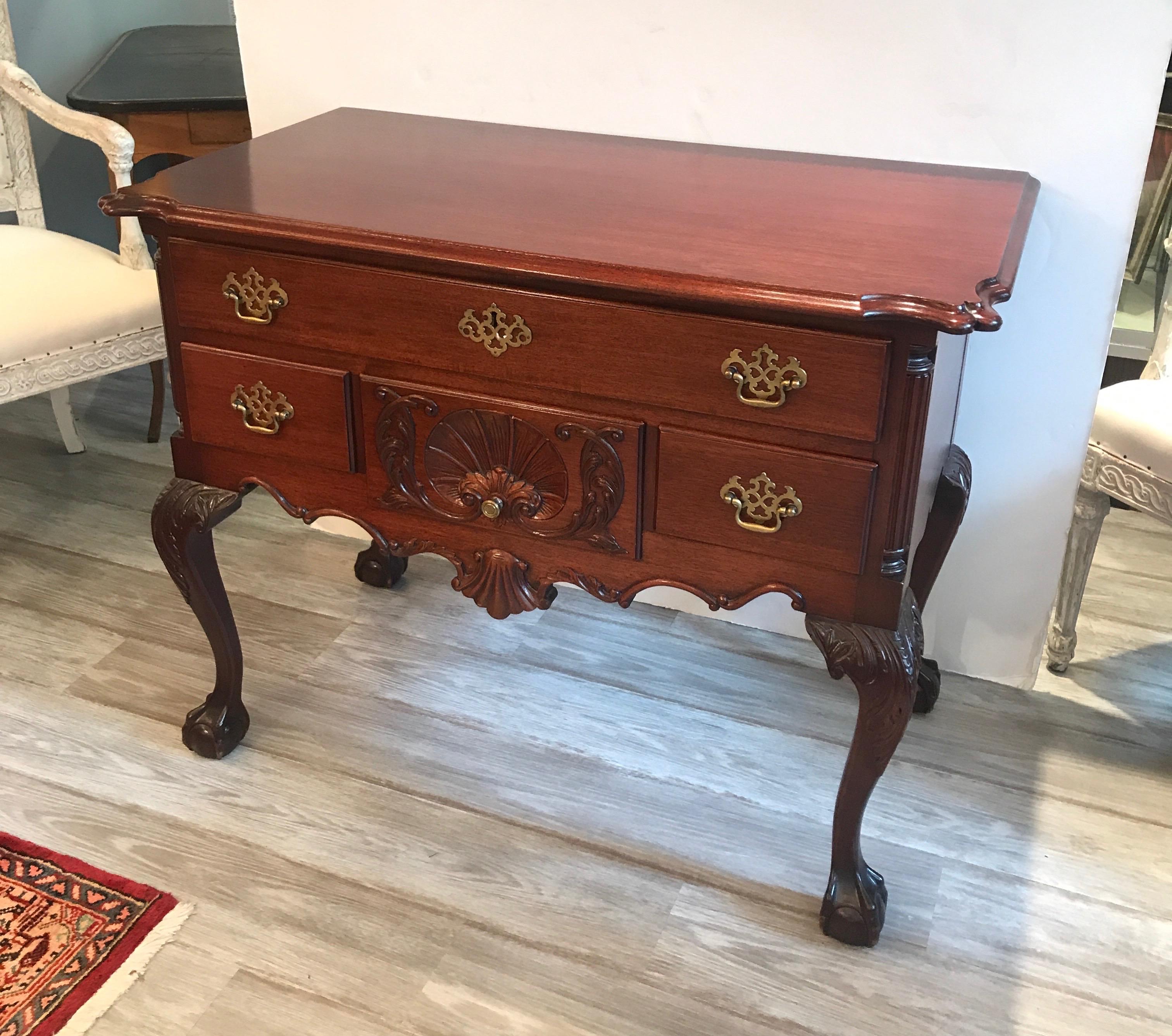 A classic Philadelphia Chippendale style hand carved mahogany lowboy. The upper long drawer with three smaller drawers resting on four hand carved acanthus leaf decorated legs with ball and claw feet. The top with scalloped corners.