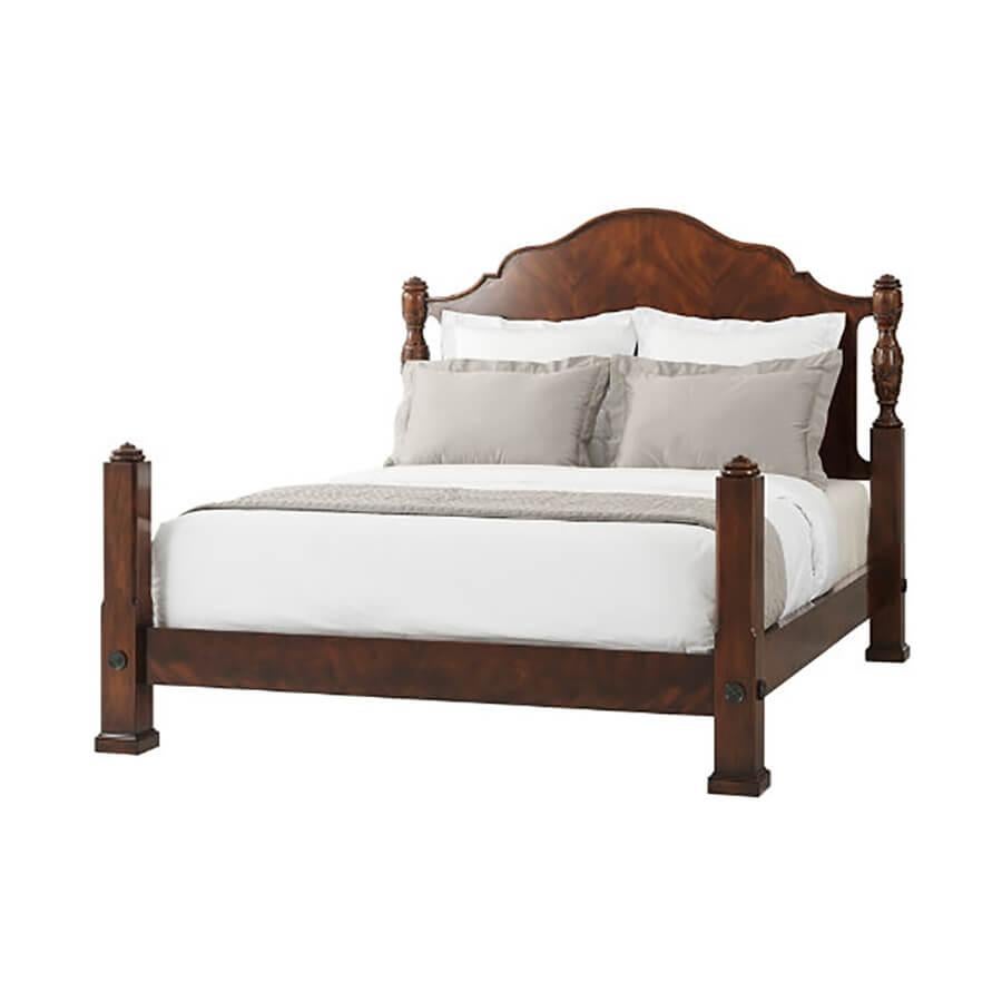 A finely carved mahogany and figured mahogany rice queen's bed, the serpentine arched and molded edge headboard flanked by acanthus leaf and rice carved baluster turned posts with urn finials, the figured mahogany rails with brass rosettes to the