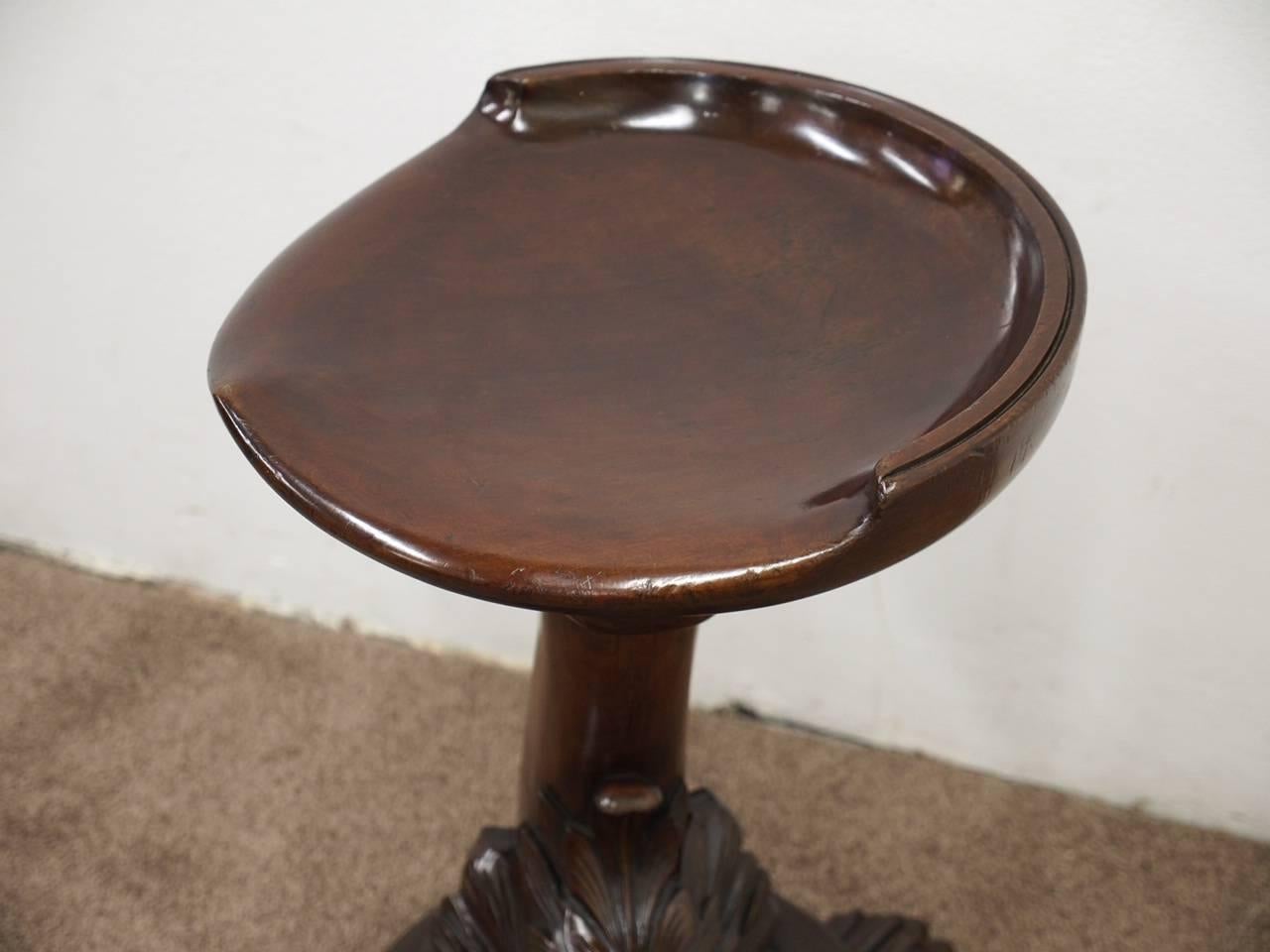 Carved mahogany revolving grotto stool, with the trade label of Edwards and Roberts, London, circa 1870. With a scooped out seat in solid mahogany and small gallery back which is fixed to a thread revolving mechanism. It has a tapering column,
