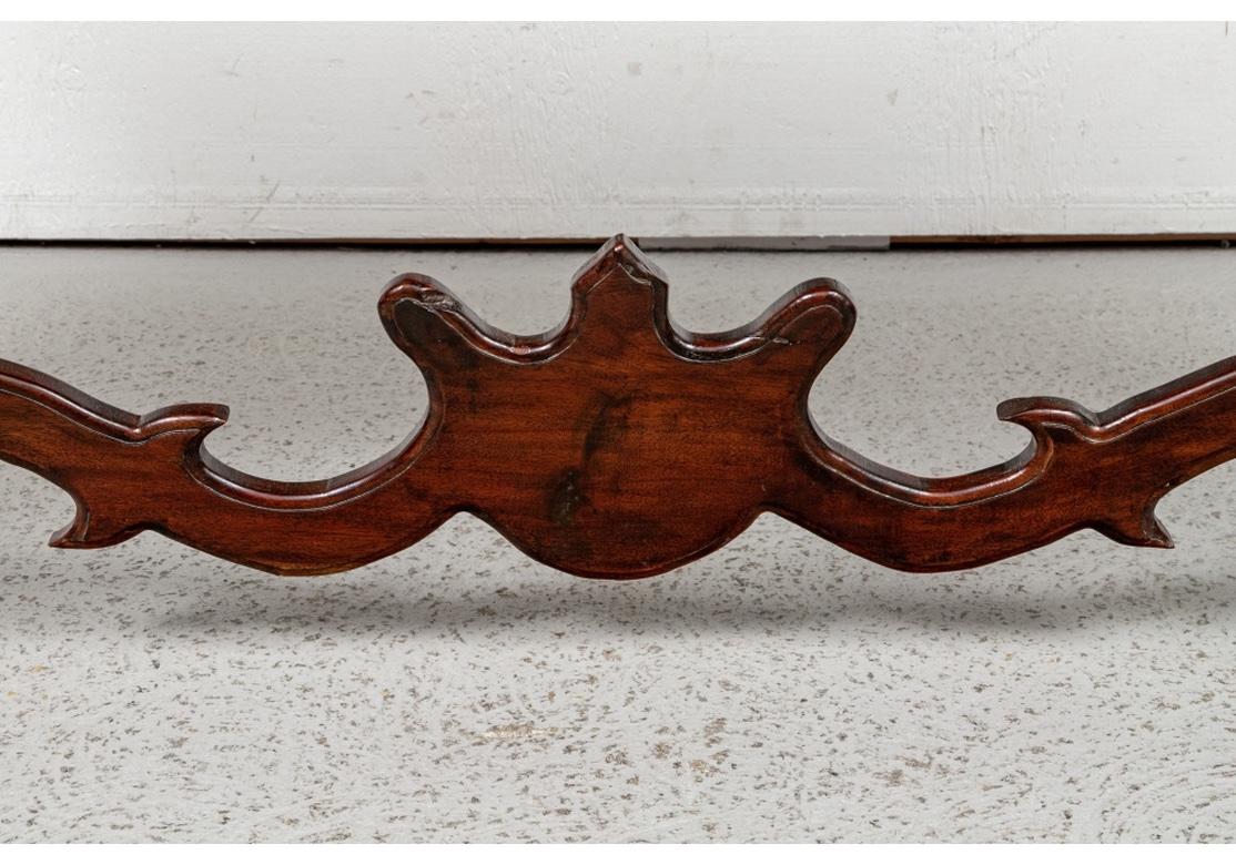 A very well made Console Table in Primitive Spanish Colonial Style with plank constructed top and carved edge. With elaborately carved serpentine supports on the side and upper center. With a complementary carved stretcher below with center crest