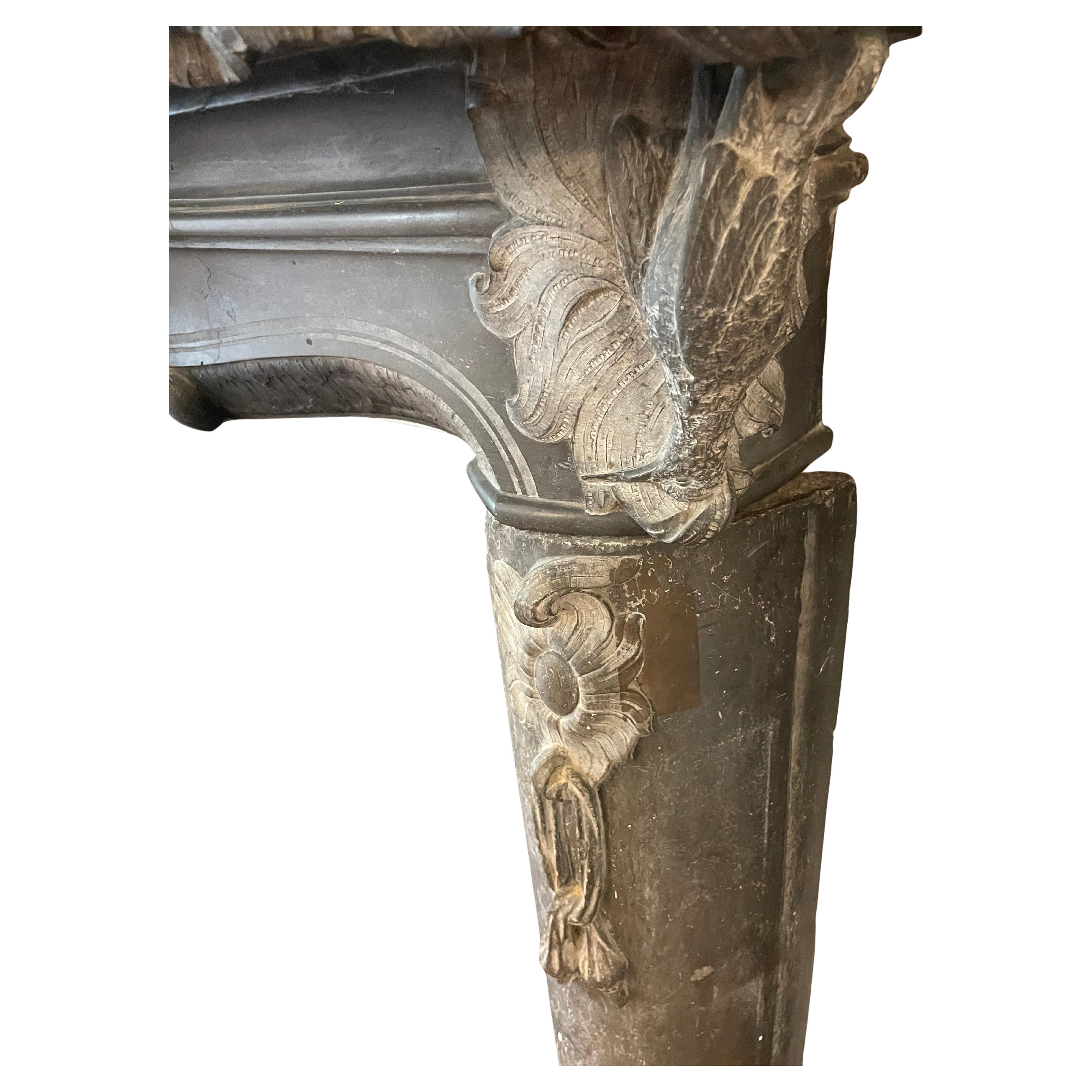 Extraordinaire cheminée autrichienne en marbre sculpté. Sculptée en marbre noir/gris. Sculpture magnifiquement détaillée représentant un chasseur sur un motif de zéphyr, flanqué de part et d'autre de perdrix et de guirlandes de sacs de grenaille. La