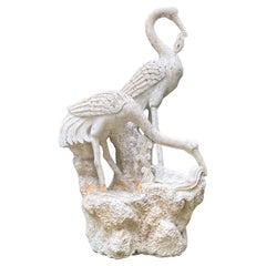 Des grues en marbre sculptées sur socle en roche
