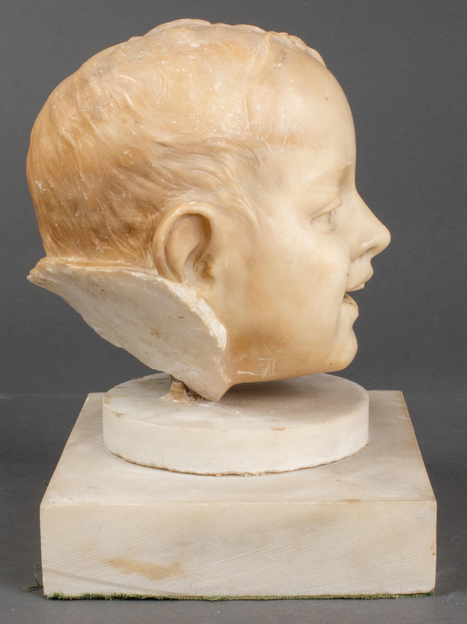 Carved marble fragment from a bust of a young boy, 20th century, his face depicted with a happy smile, unsigned, with associated white marble base. Measures: Bust 7.75” H x 6” W x 6.5” D, base 6.25