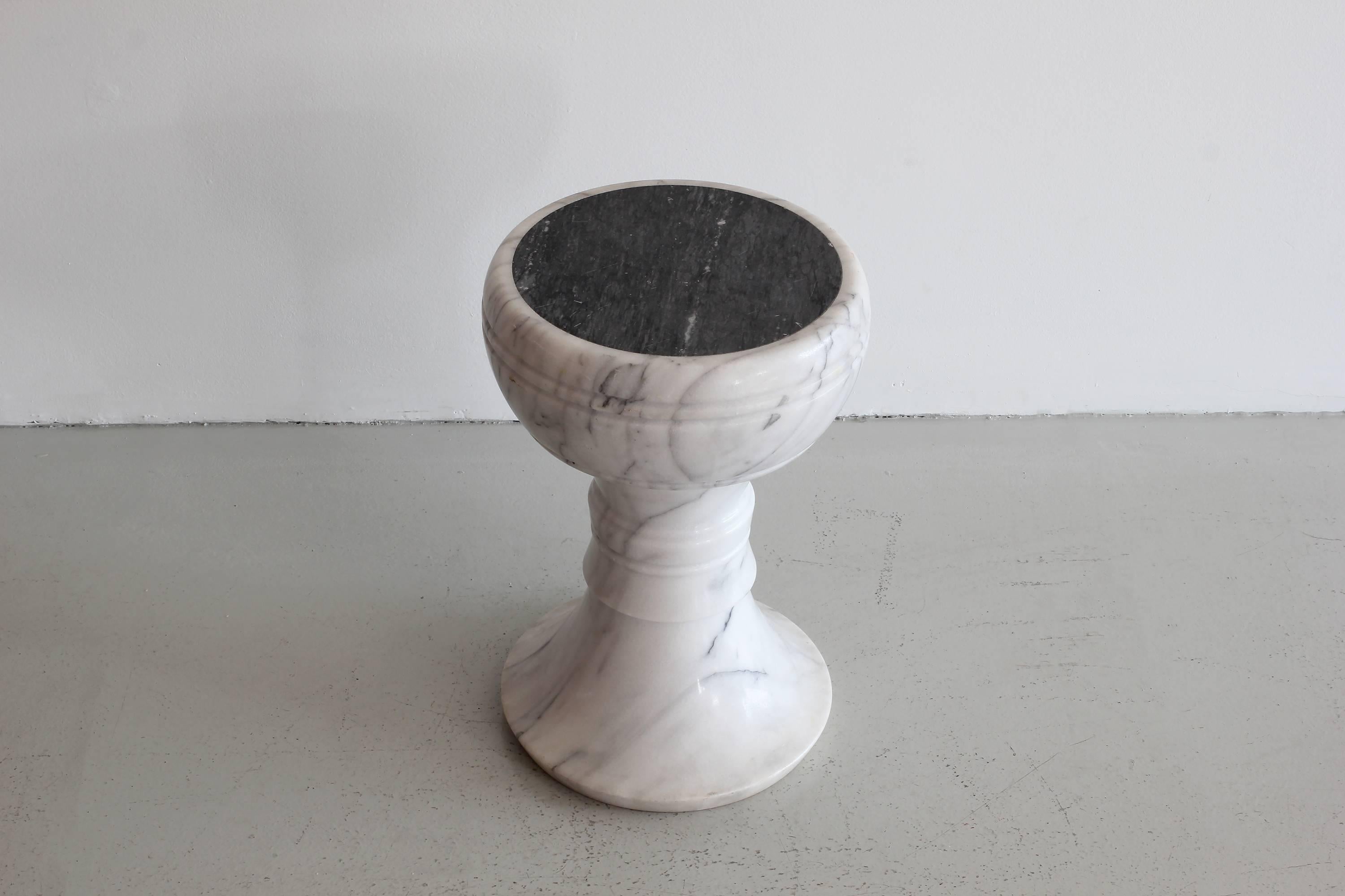 Beautiful solid Carrara marble stool. Each seat has solid black marble inlaid tops and is carved from a solid piece of marble. Carrara marble has beautiful grey swirling creating each 