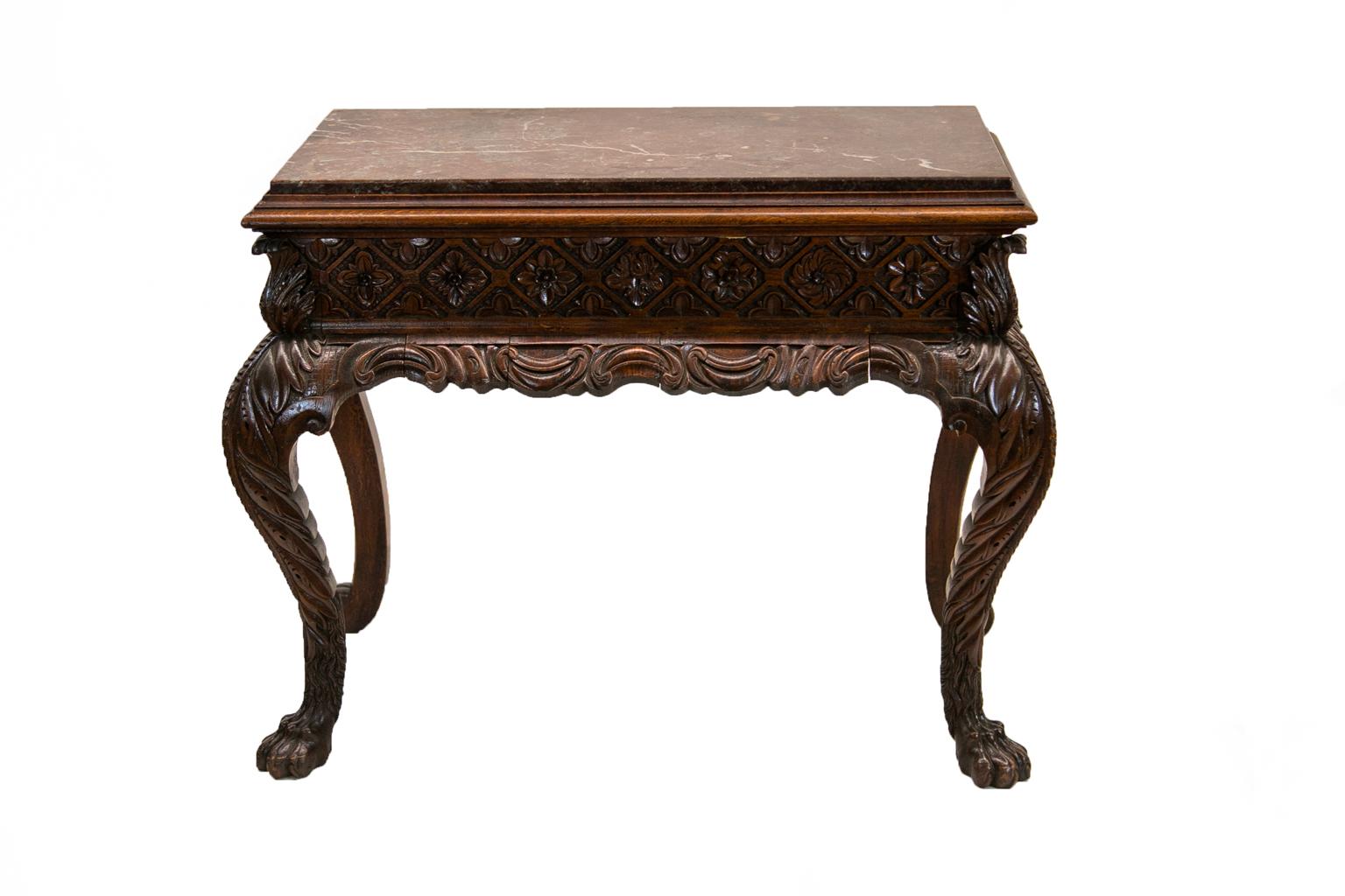 The marble-top of this carved marble-top console table is framed with heavy double molding. The top is removable. The frieze is carved with repeating diamond and circle patterns enclosing floral carvings in high relief. The corners have carved