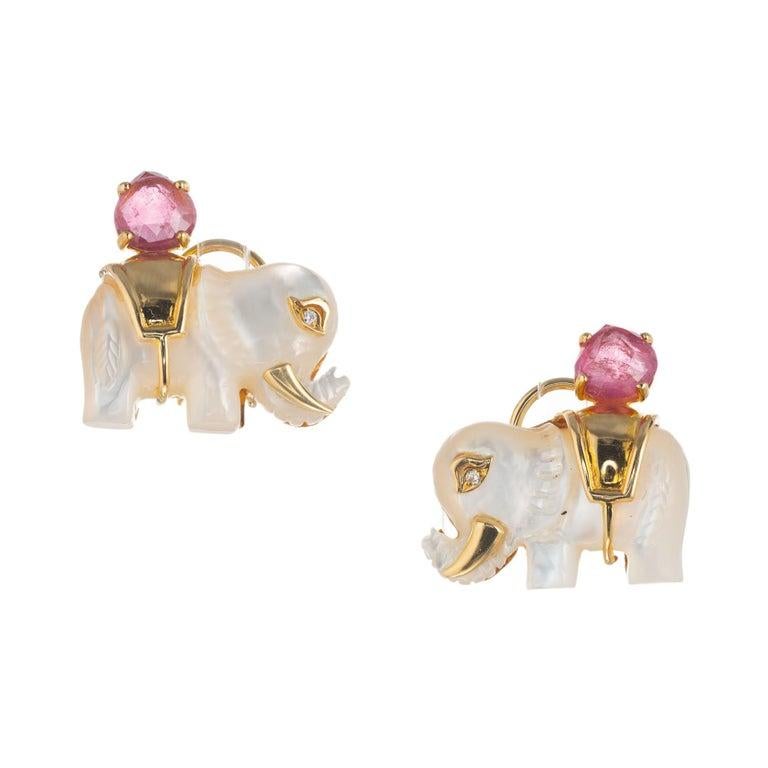 Carved mother or pearl tourmaline diamond 18k yellow gold elephant earrings. 2 mother of pearl carved elephants accented with 2 round pink tourmaline's and 2 round brilliant cut diamonds. 

2 mother of pearl carved elephants
2 faceted pink