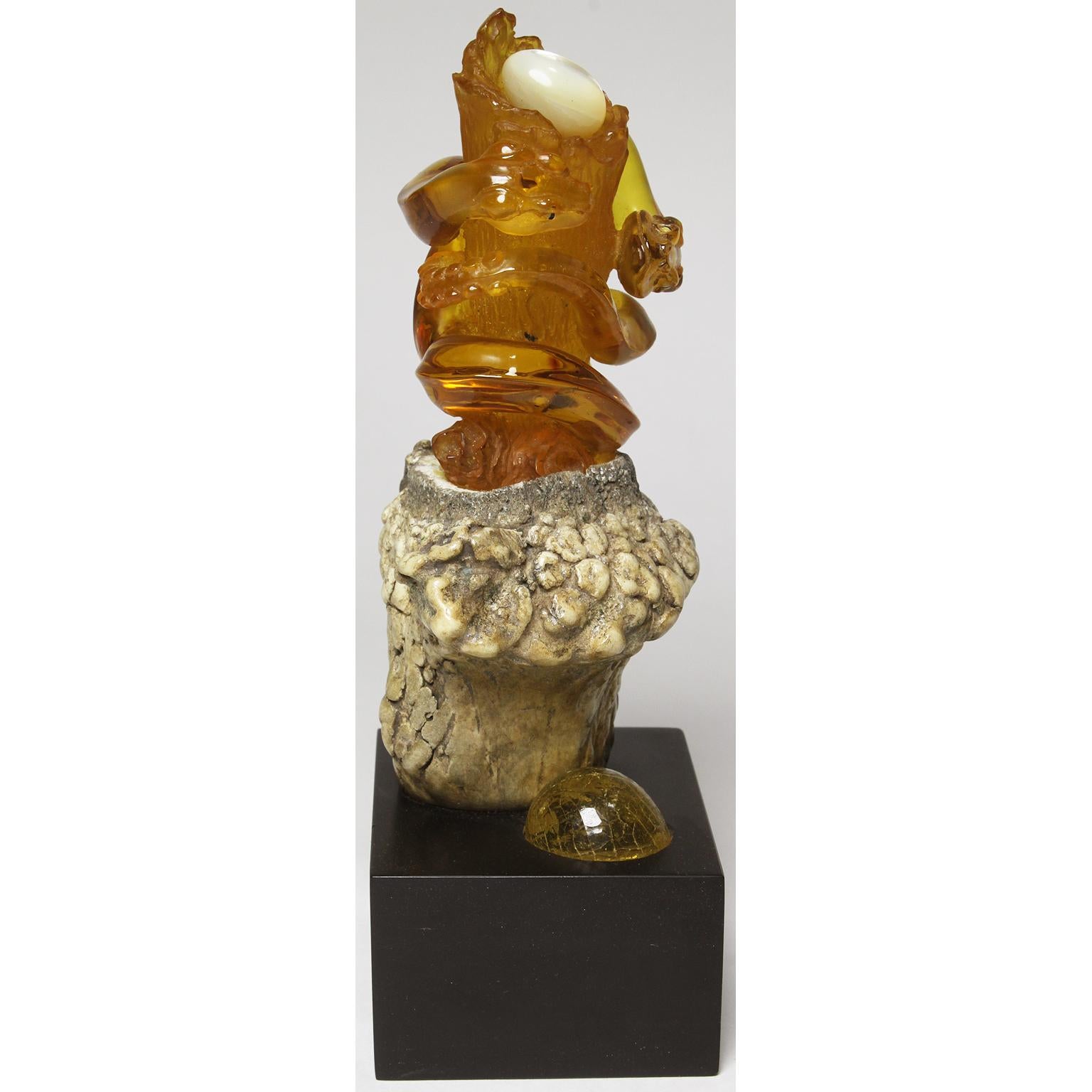 Un groupe de serpents et leur nid, finement sculpté en ambre naturel, dans un spécimen d'ambre de grande taille très clair provenant du Chiapas, au Mexique. La sculpture, représentant deux serpents entrelacés autour d'un tronc d'arbre, repose dans