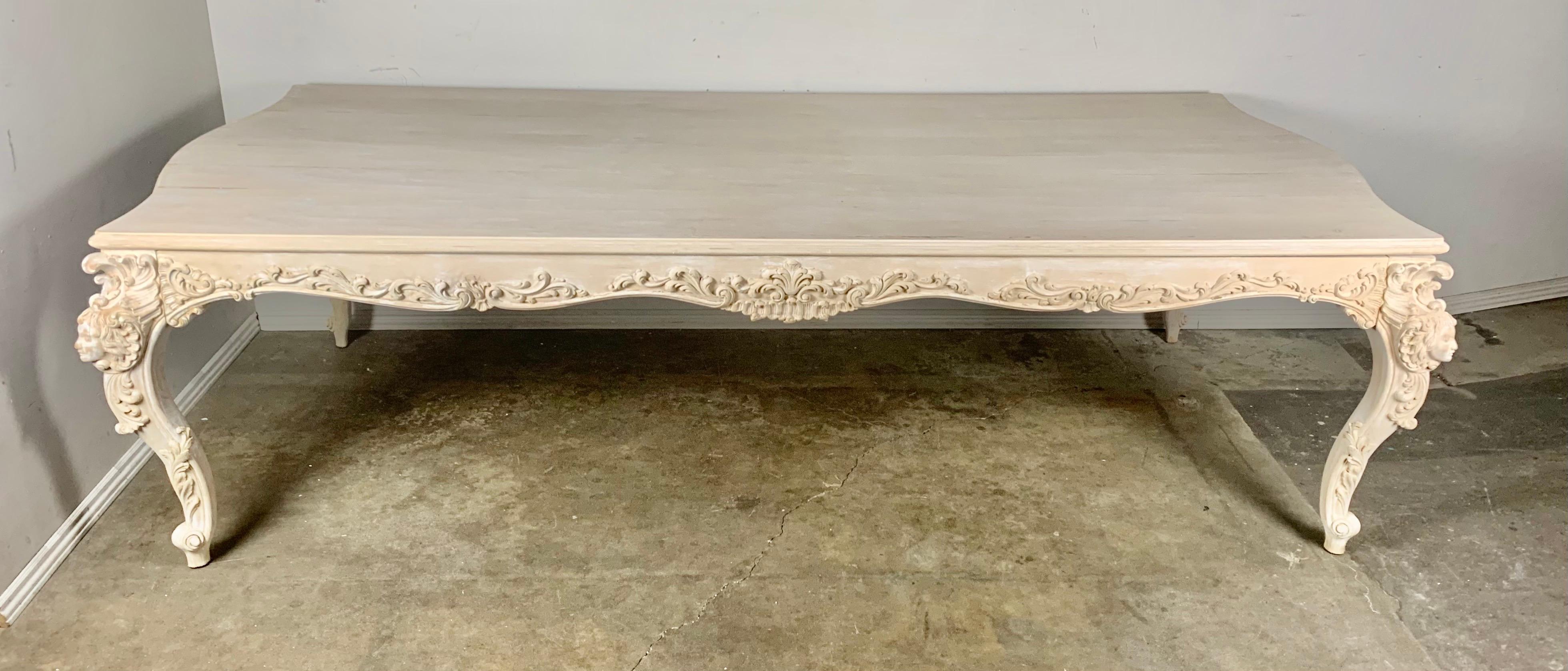 French carved dining table that stands on four cabriole carved legs with Cherub Faces on all corners. The scalloped apron also has beautiful carving throughout. There are small remnants of paint that remain throughout the table.