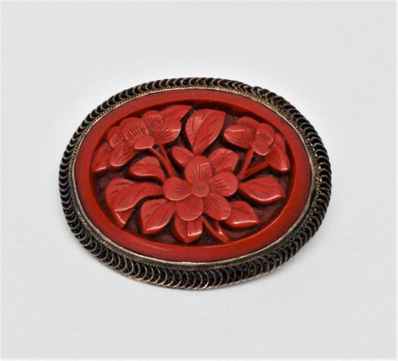 Beautifully carved in natural coral, this artisan brooch has warm heirloom appeal. Framed in sterling silver, the hand tooled oval measures 1-3/8 x 1-1/8 inches. This antique brooch can be worn horizontally or vertically and is outfitted with