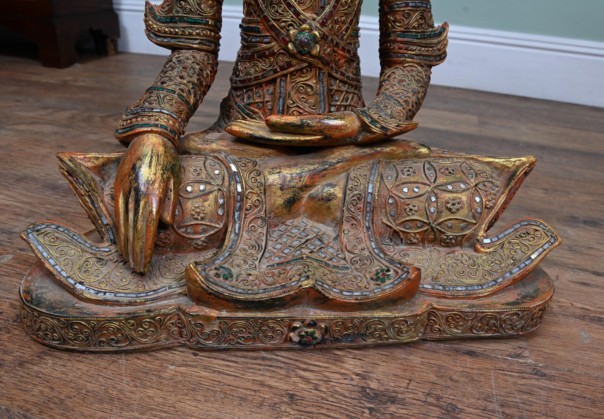Buda nepalí decorativo sentado y tallado en la clásica postura de meditación del loto Este buda de madera tallada está adornado con espejos transparentes, rojos y verdes en un diseño de mosaico
Alrededor de 1930
Esto añadirá serenidad y calma a