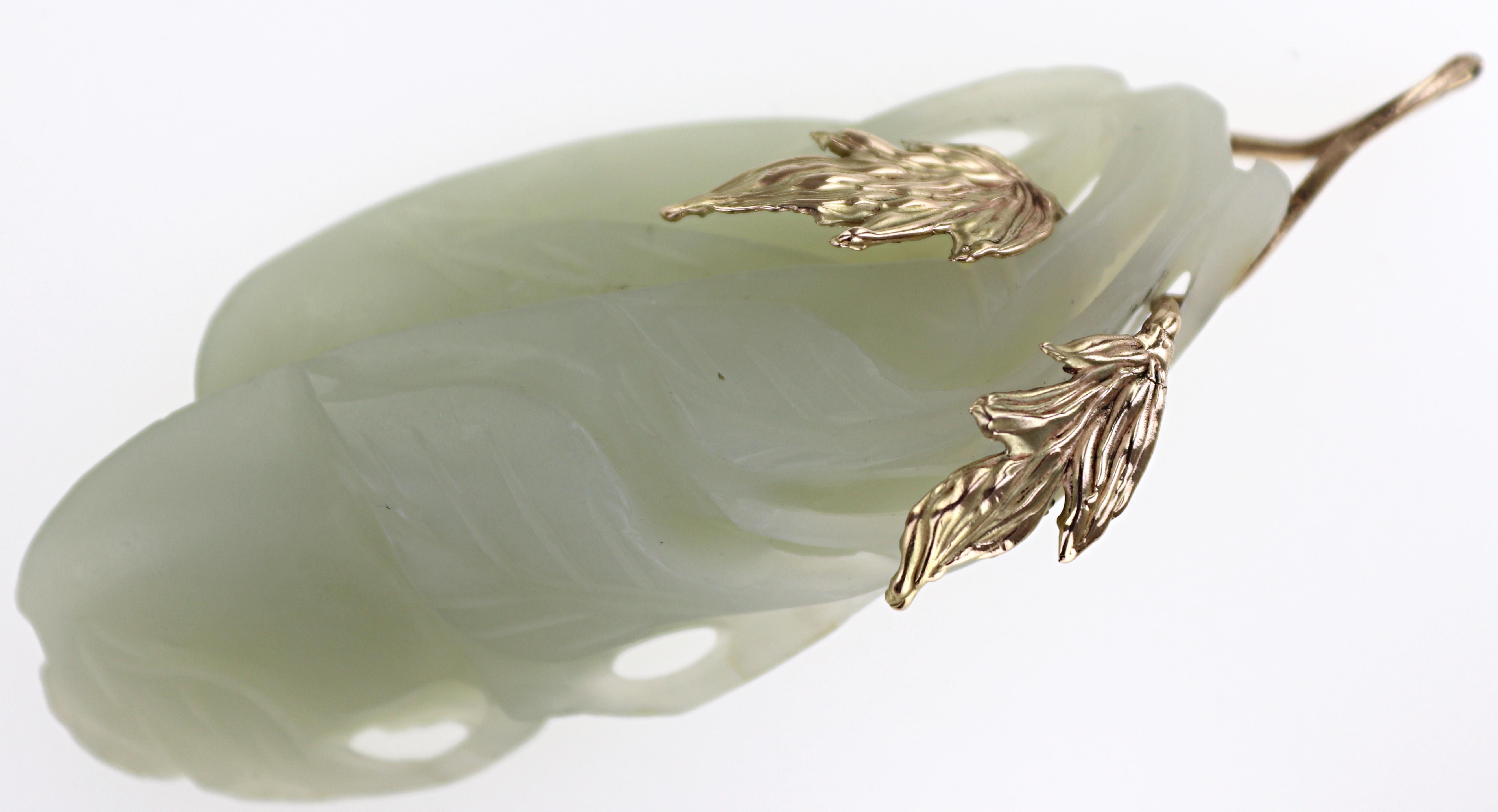 Featuring (1) carved nephrite jade, 65.8 X 29.1 X 13.2 mm, depicting gourds and leaves, completed by a 14k yellow gold wire leaf bail, Gross weight 32.04 grams.