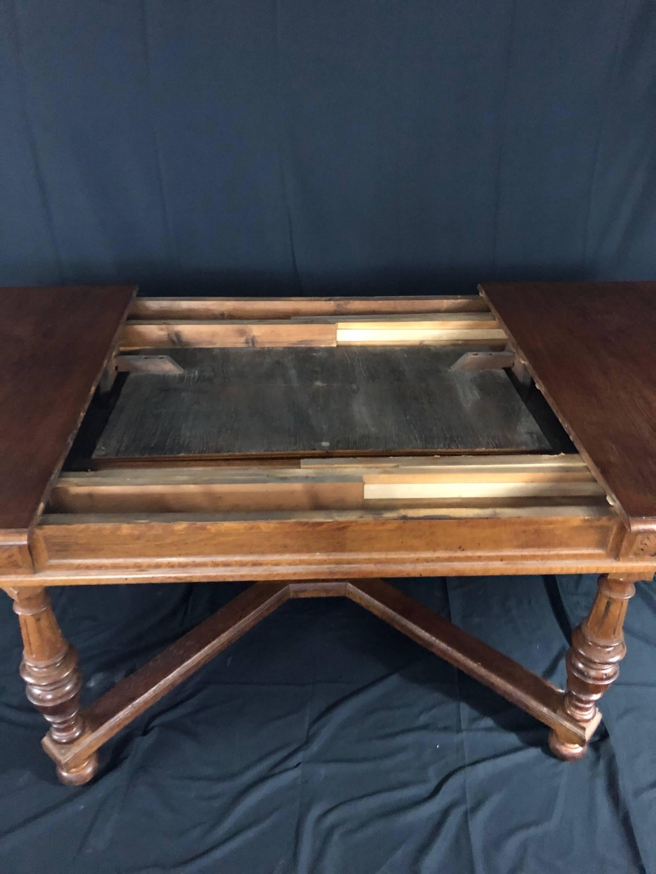 A versatile Art Deco or Arts & Crafts oak dining table having inset draw leaf that, once the sides are pulled apart, pops up to extend the table width from 52.5” to 91 inches. All in carved solid oak, the dining table is in the refectory style